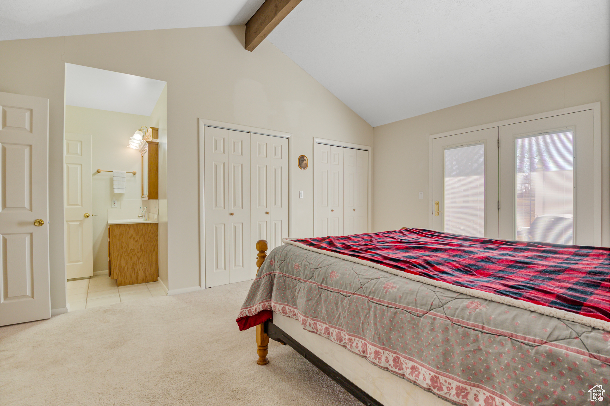 Prfimary Bedroom featuring lofted ceiling with beam & access to exterior, multiple closets, ensuite bathroom