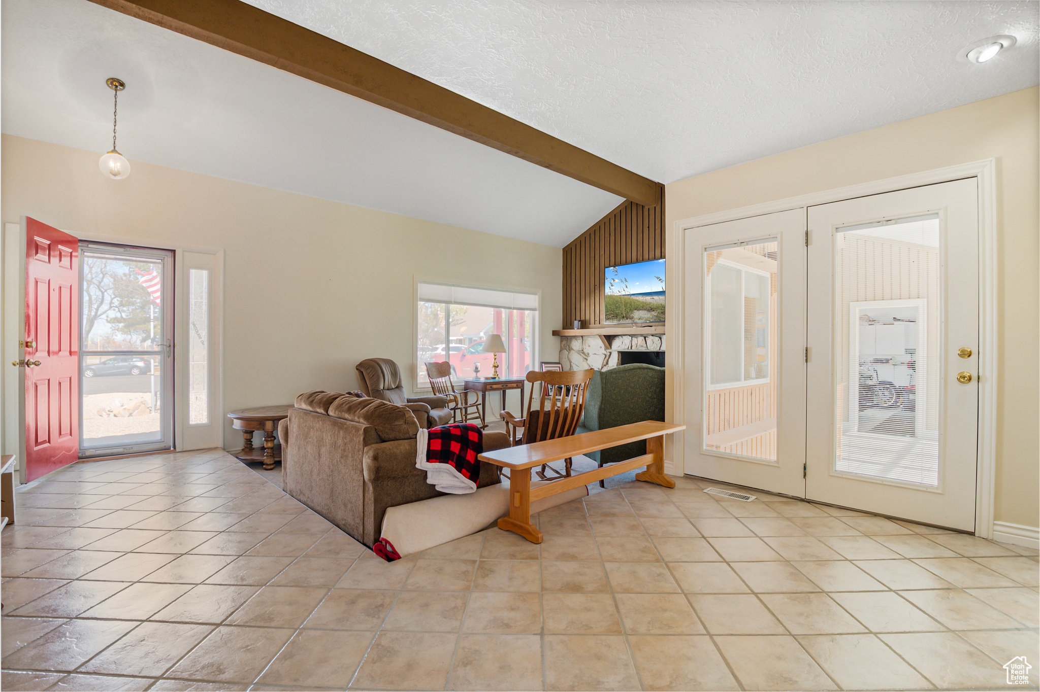 Living area featuring tile floors and vaulted ceiling with beam