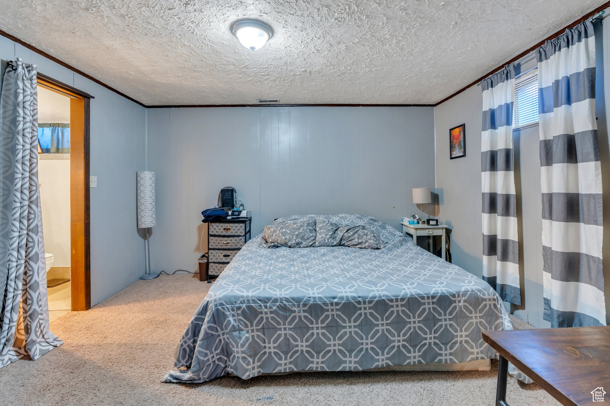 Bedroom featuring crown molding, visible vents, carpet floors, and a textured ceiling