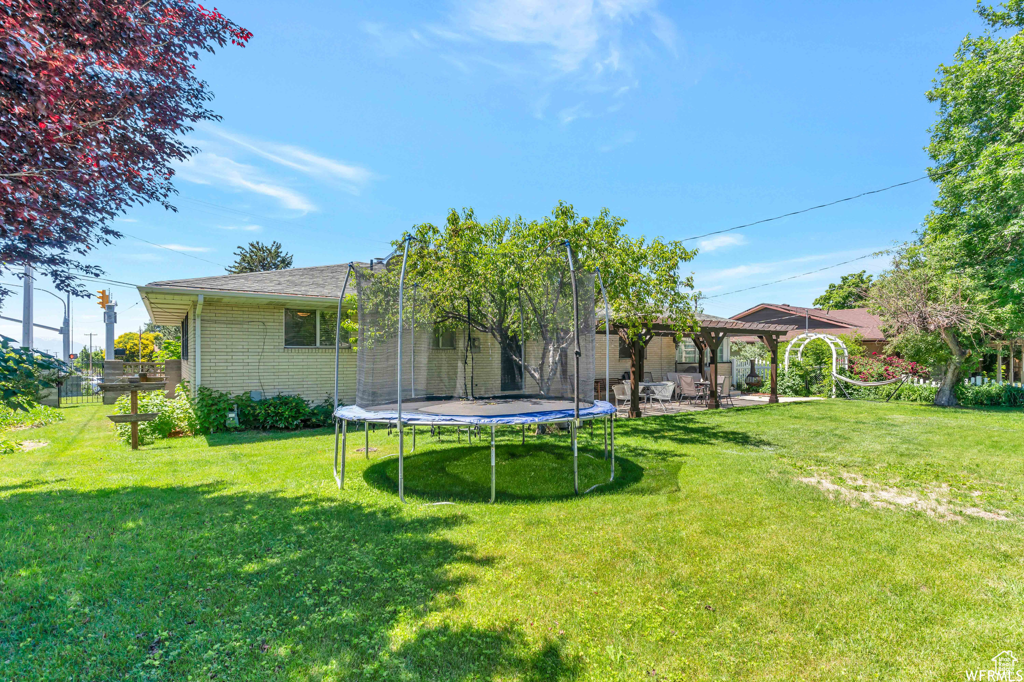 View of yard featuring a patio area, a trampoline, and fence