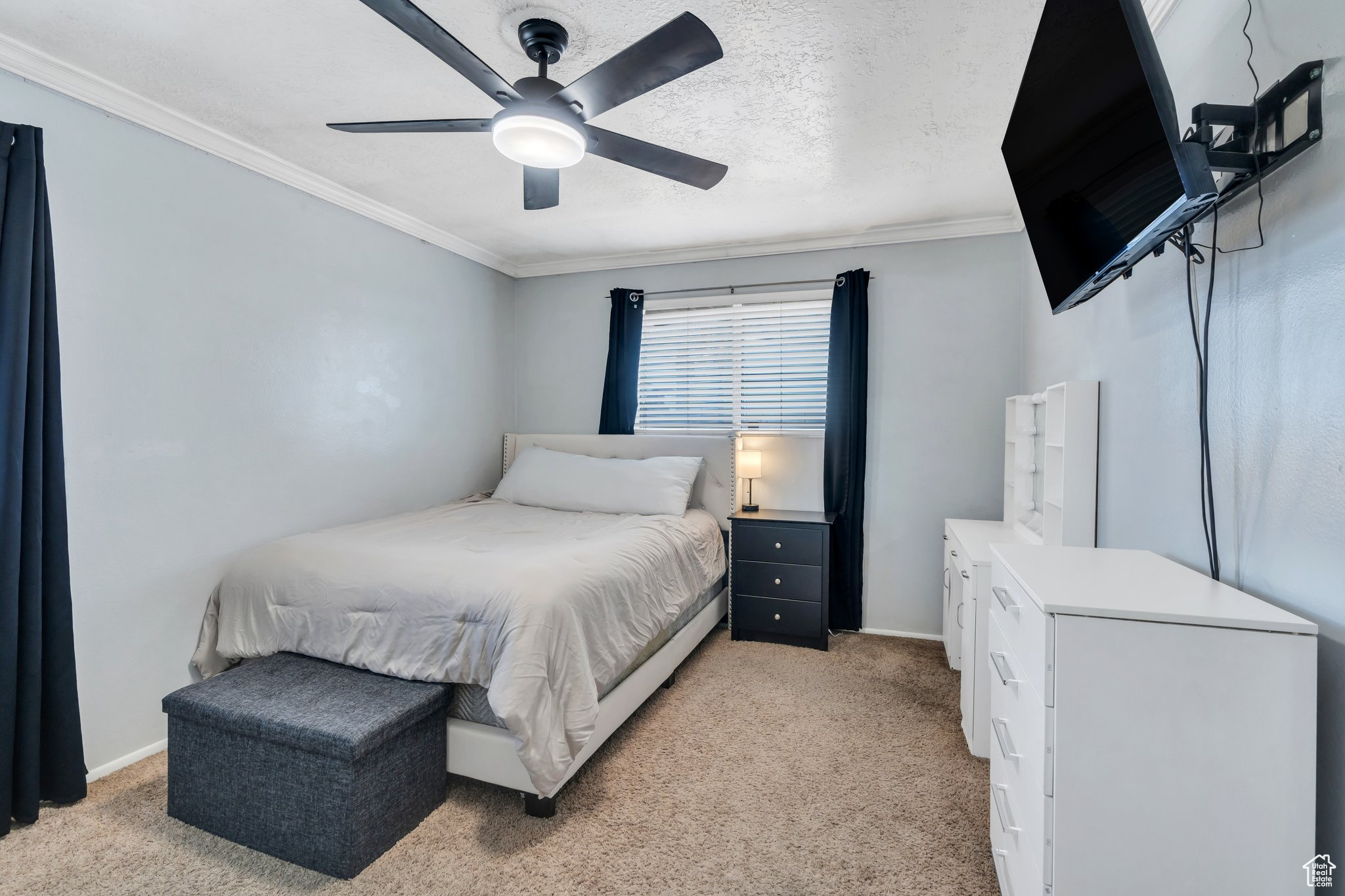 Bedroom with baseboards, light colored carpet, crown molding, and a textured ceiling