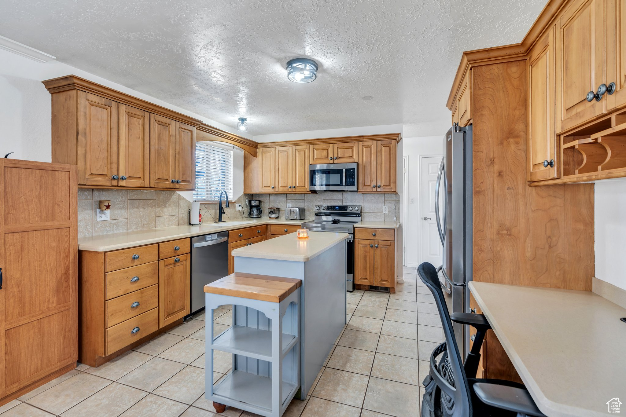 Kitchen with open shelves, stainless steel appliances, a center island, and light countertops
