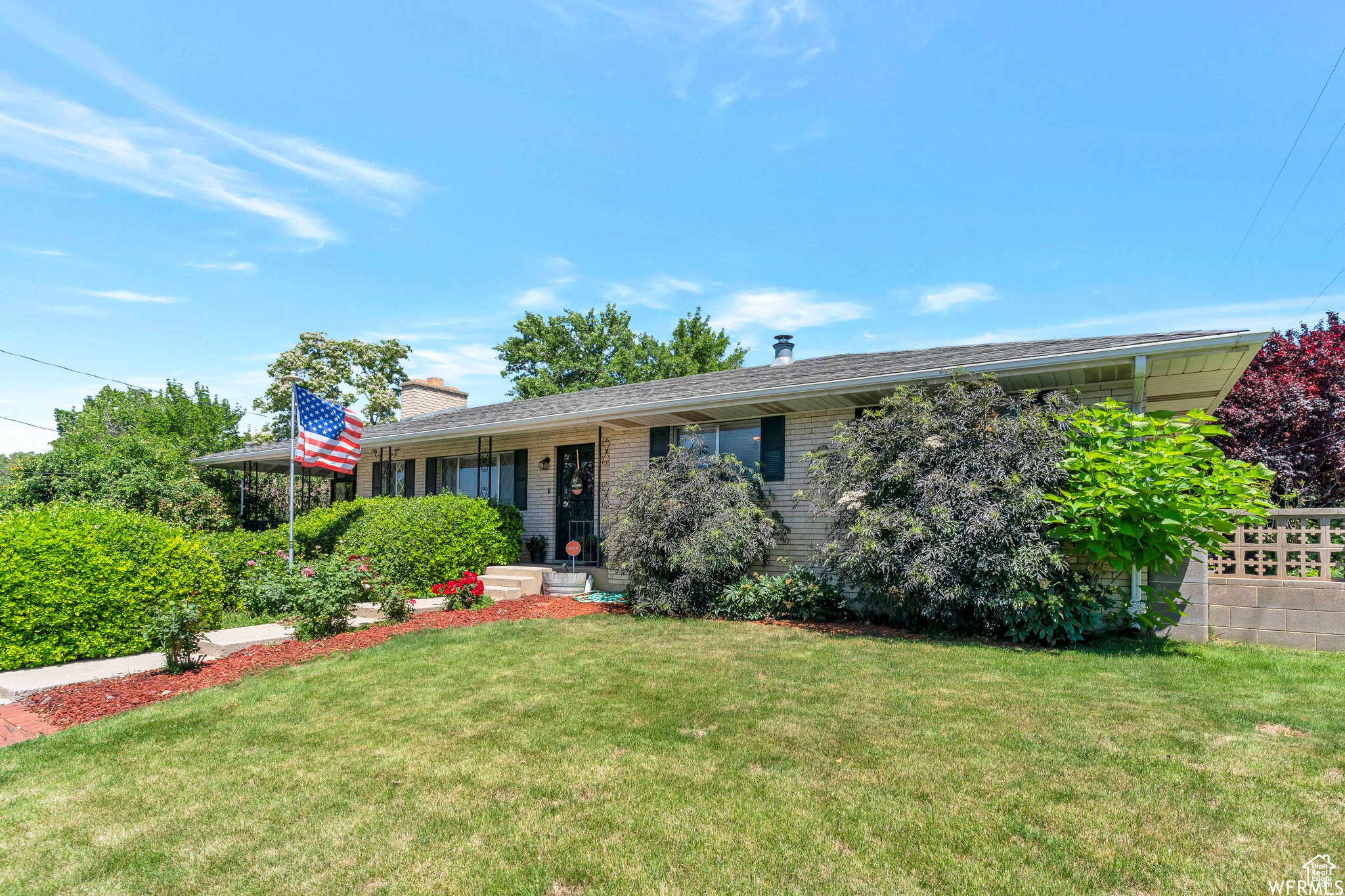 Ranch-style home with brick siding, a chimney, and a front lawn