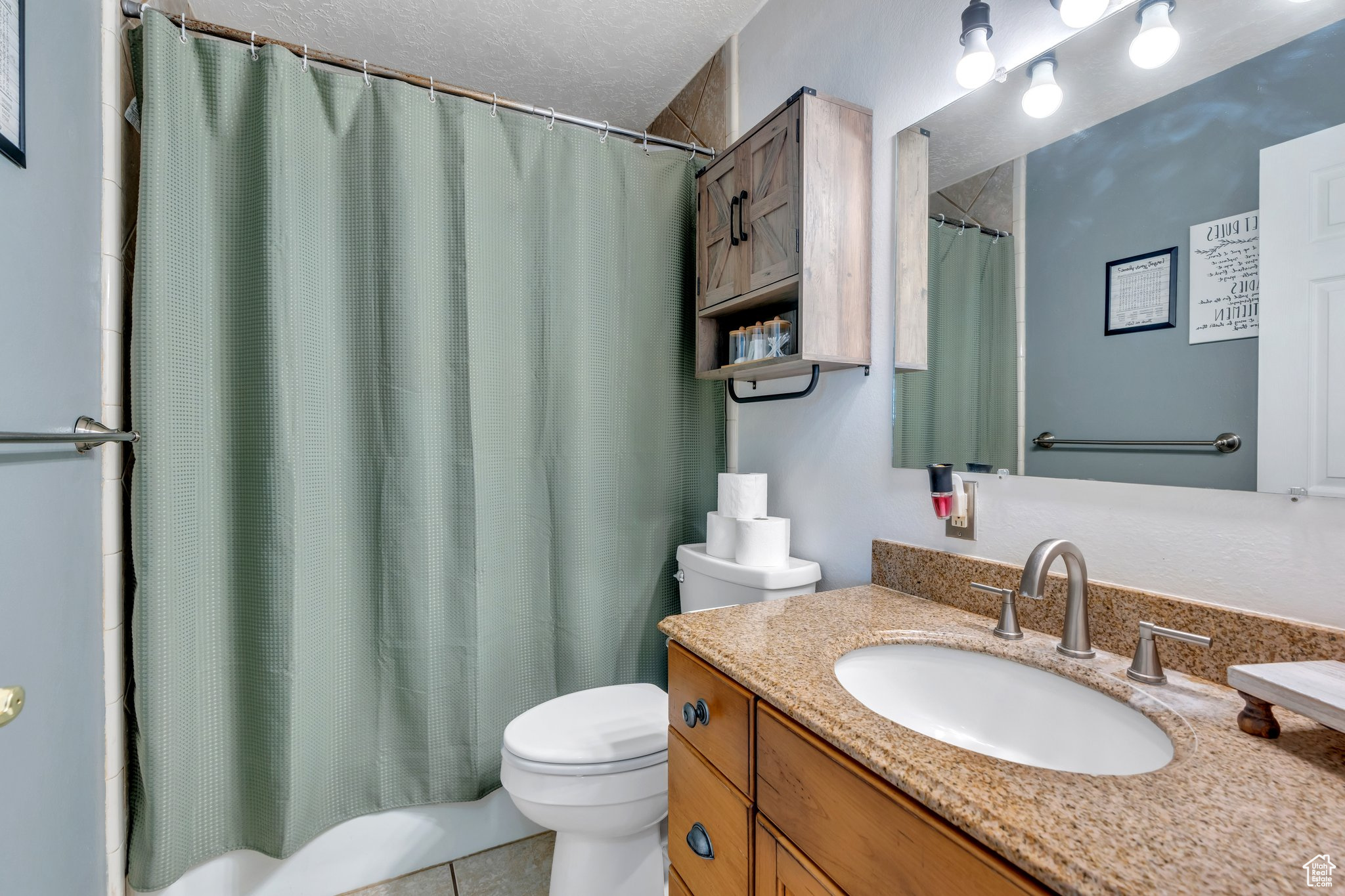 Full bathroom featuring vanity, a textured ceiling, tile patterned floors, toilet, and shower / tub combo with curtain