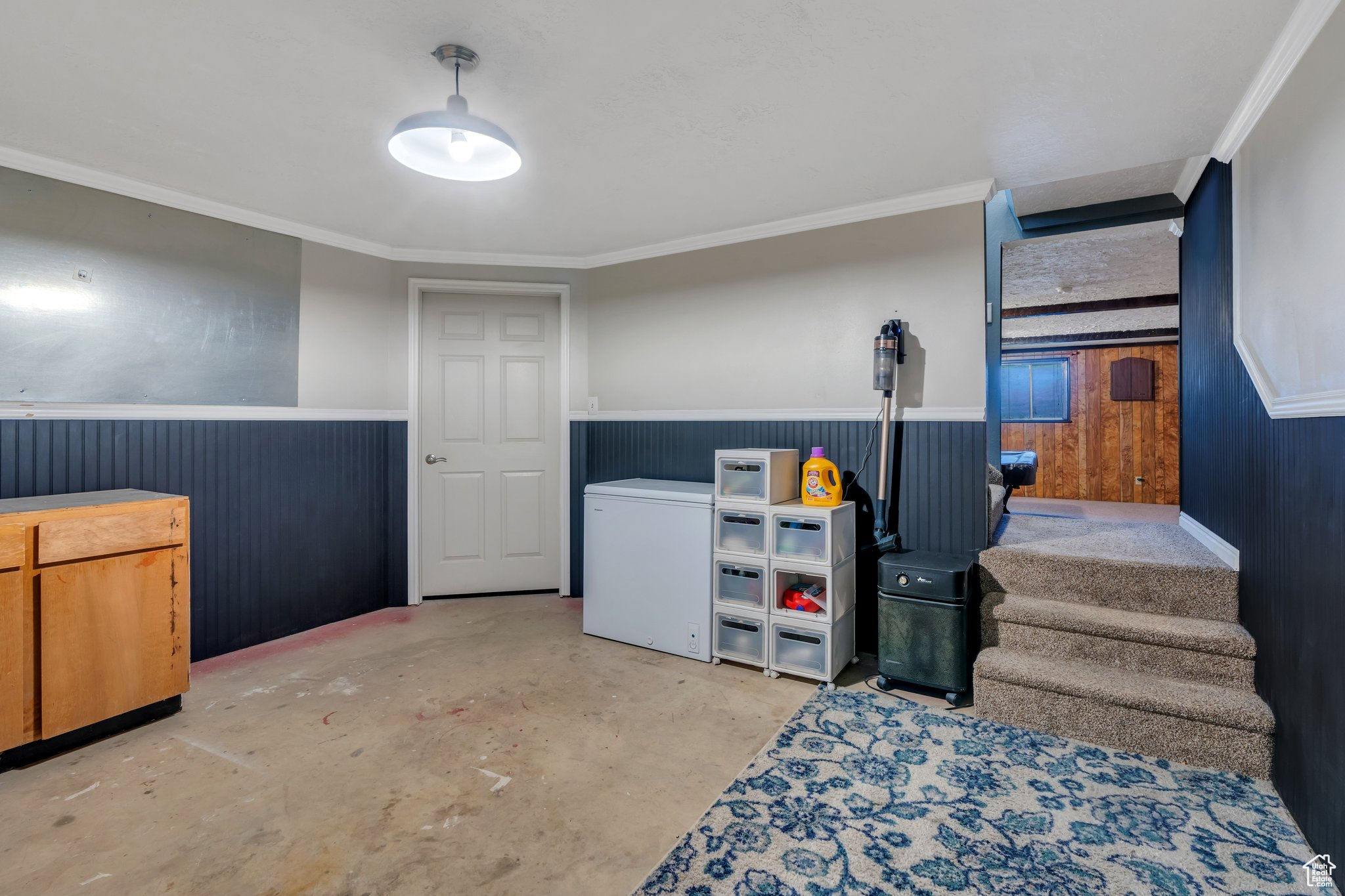 Below grade area featuring wainscoting, refrigerator, stairs, and crown molding