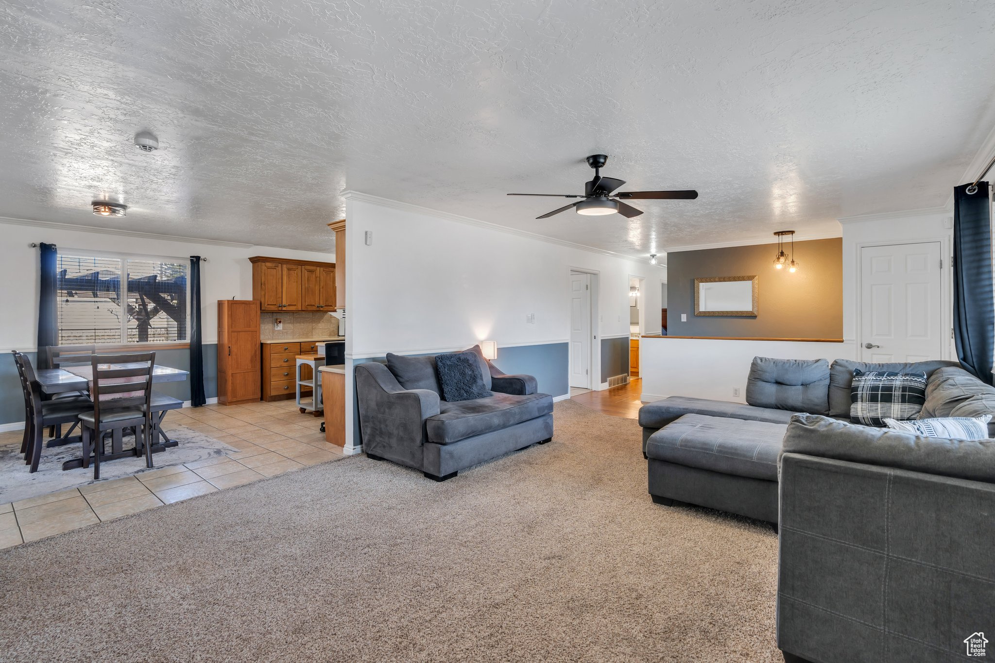 Living room featuring light tile patterned flooring, a textured ceiling, light carpet, and a ceiling fan