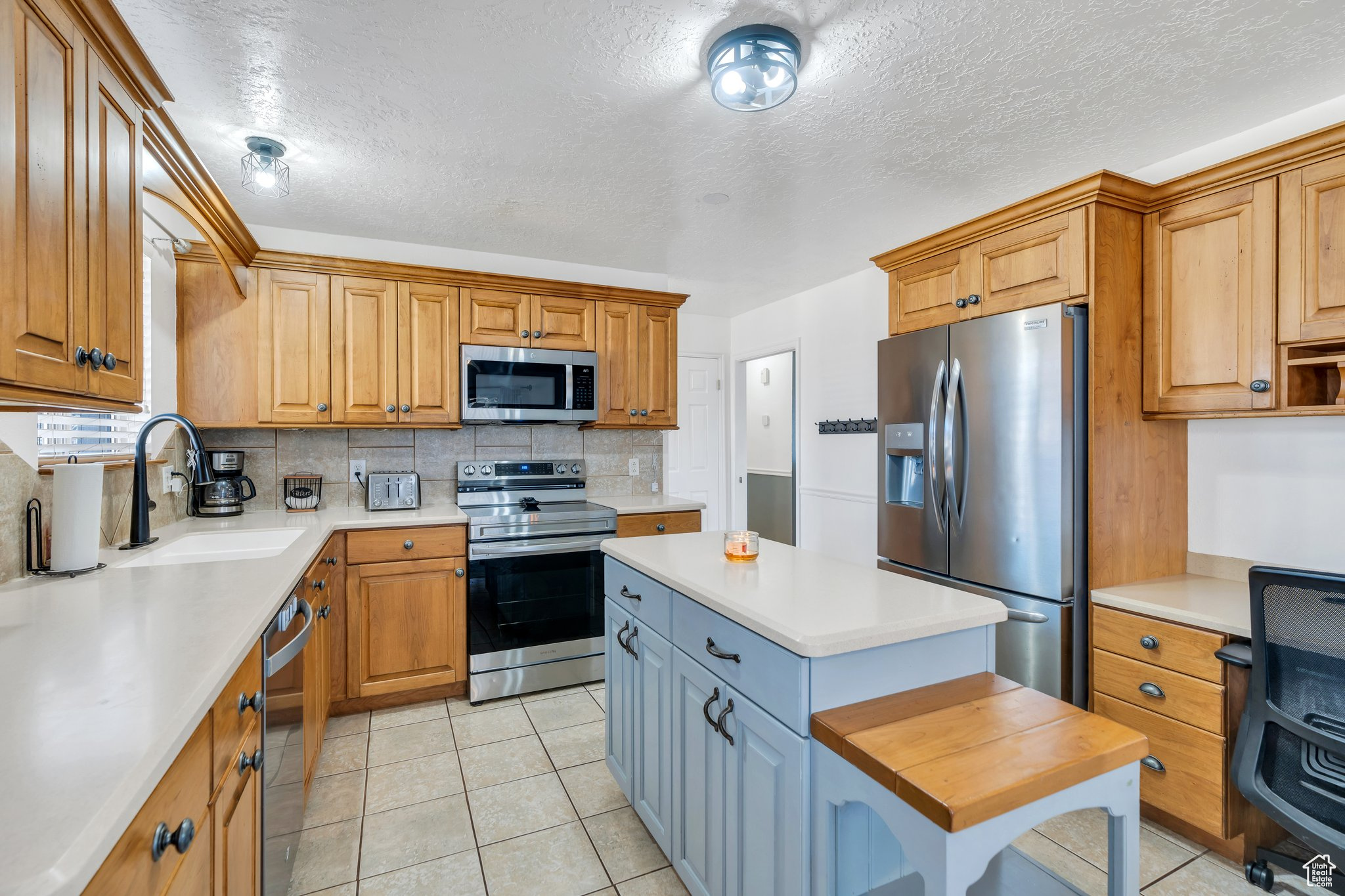 Kitchen featuring a sink, tasteful backsplash, appliances with stainless steel finishes, and light countertops