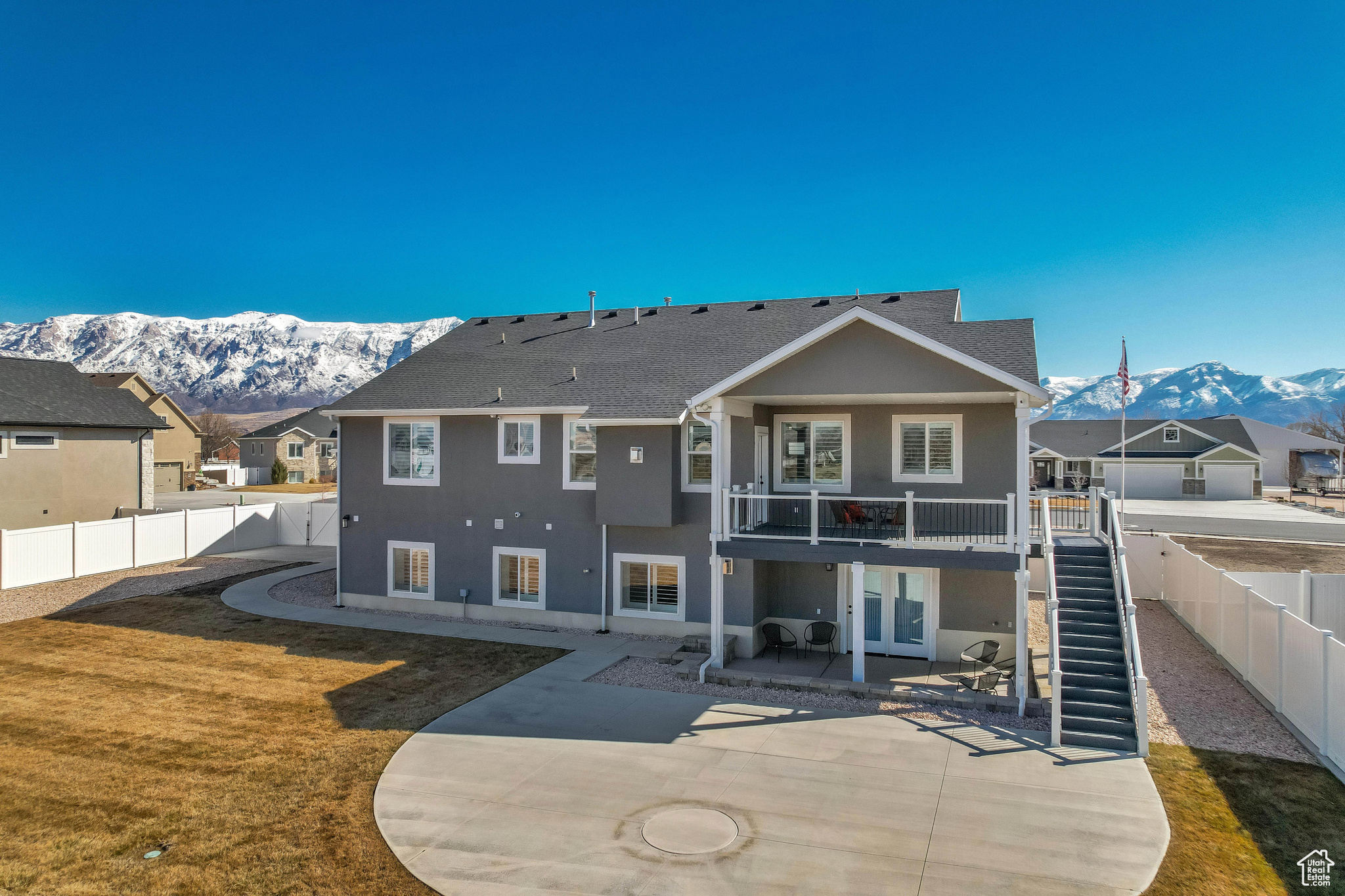 Rear view of house with stairway, a large concrete patio area, a mountain view, and a fenced backyard