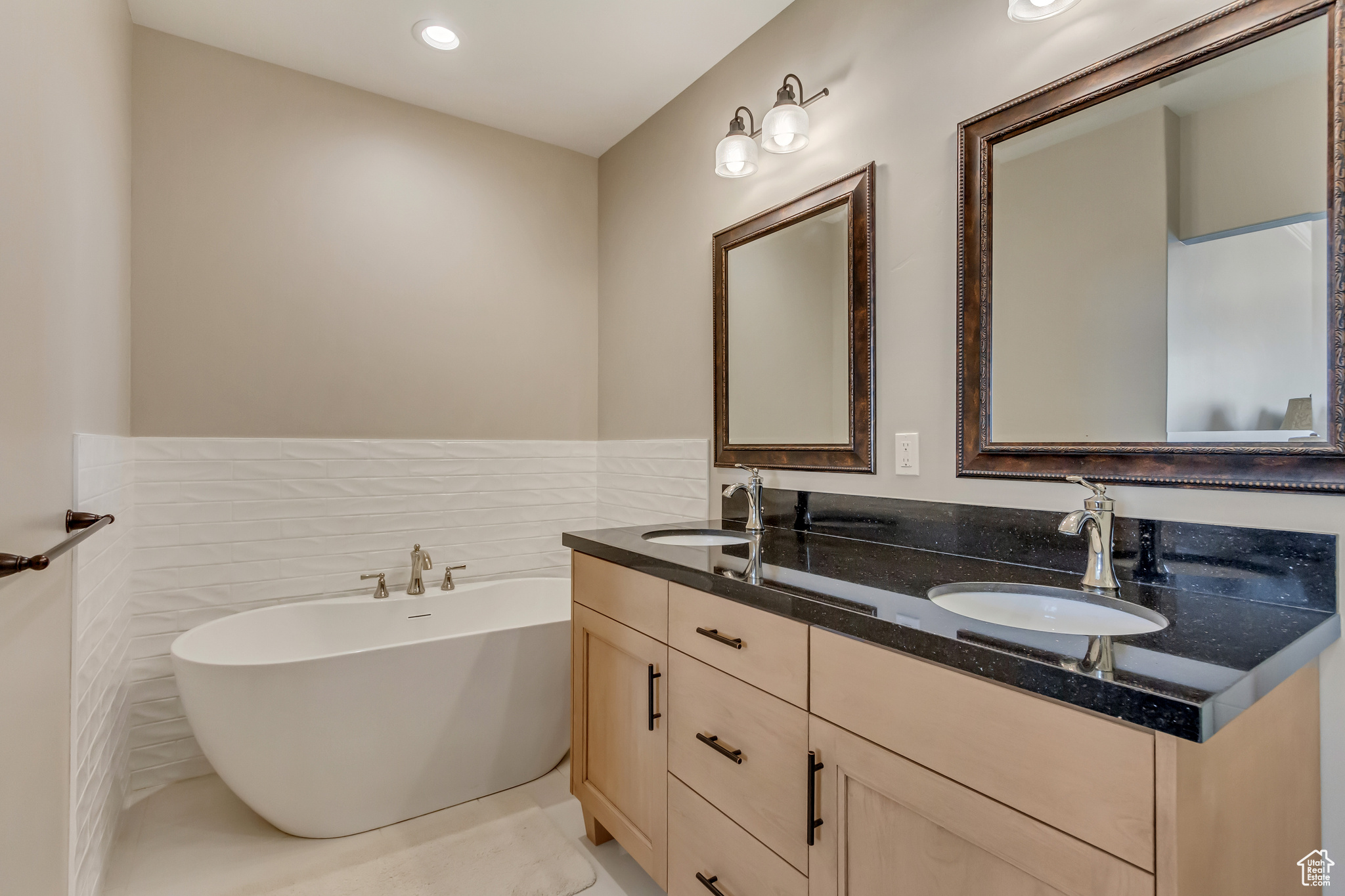Downstairs In-law suite primary bathroom with double vanity, a freestanding bath, tile walls.