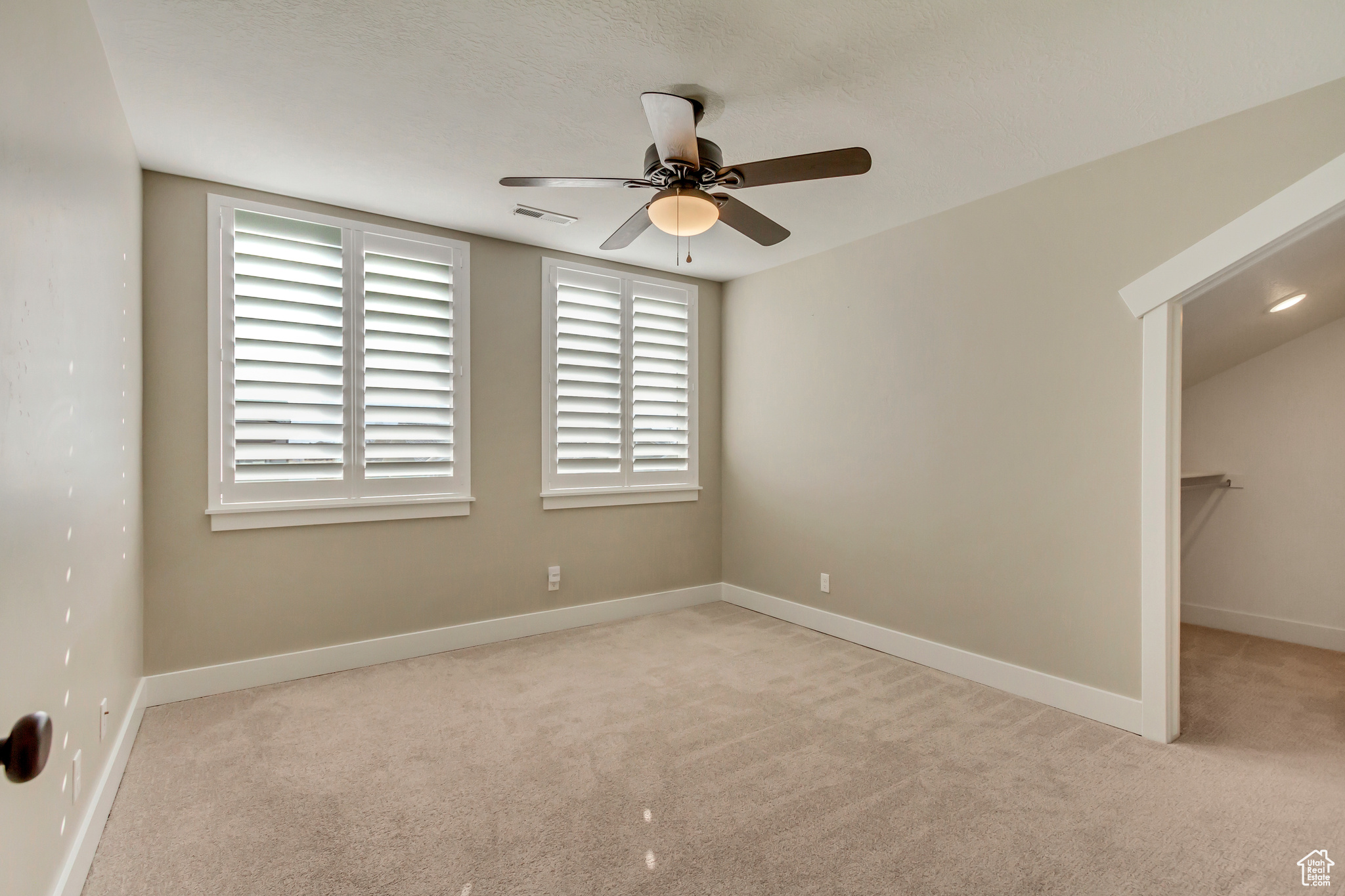 Upstairs bedroom (3) featuring  a walk in closet, carpet, baseboards, and ceiling fan.