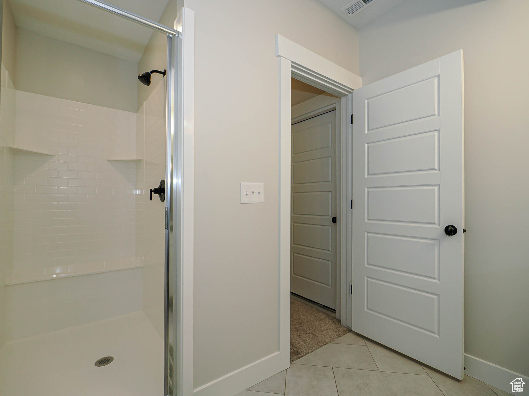 Bathroom with a stall shower, tile patterned flooring, and baseboards