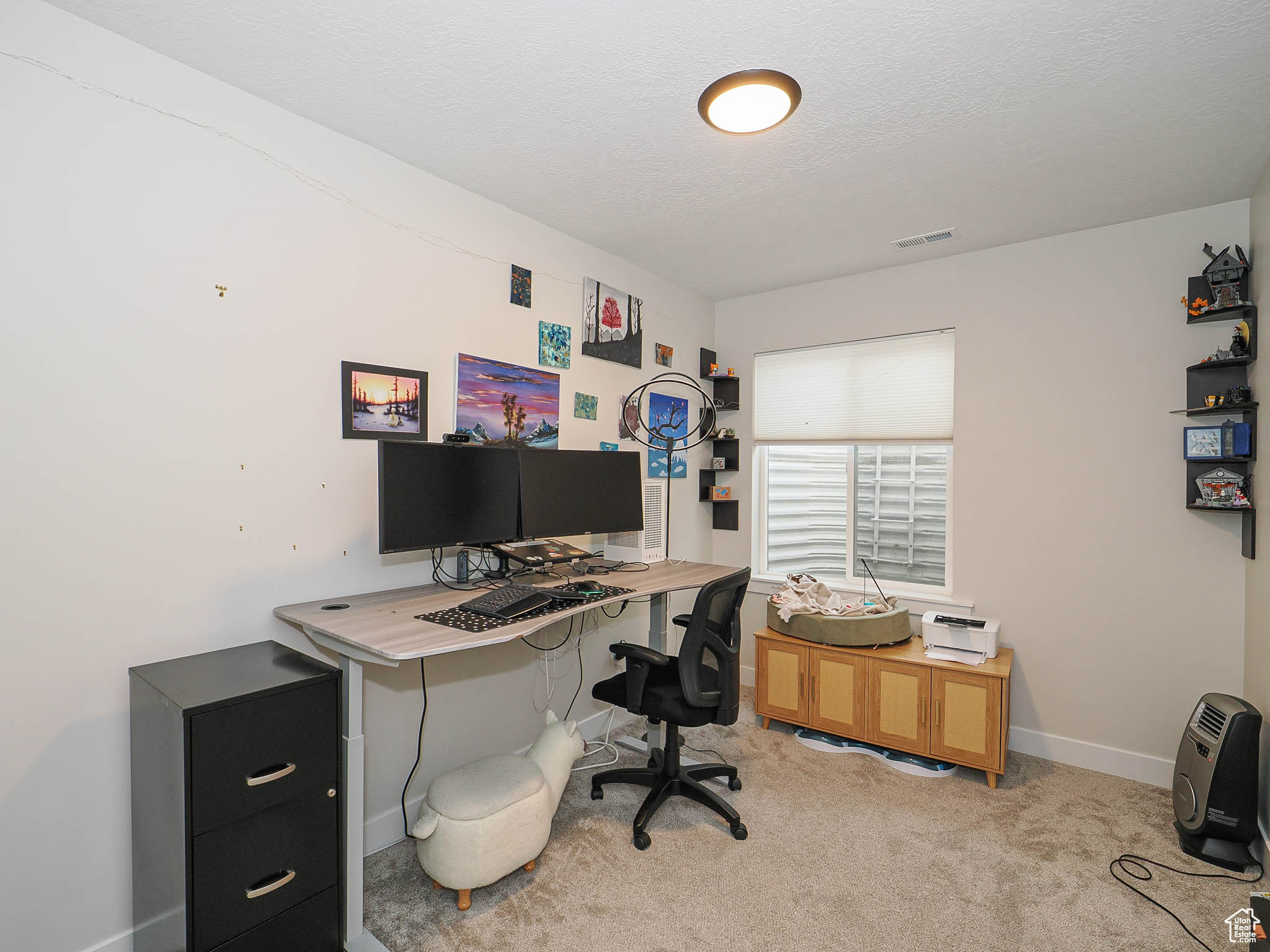 Home office featuring light carpet, baseboards, visible vents, and a textured ceiling