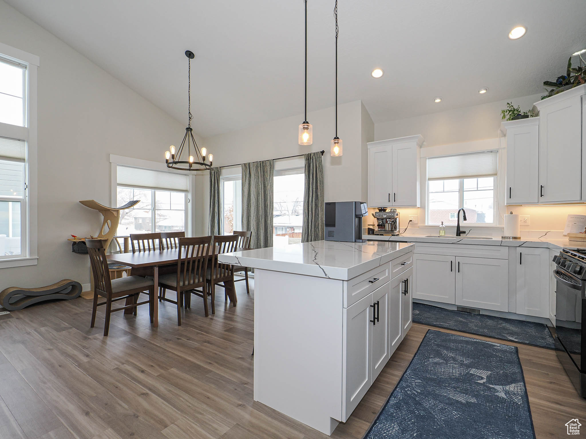 Kitchen with a center island, pendant lighting, gas stove, white cabinetry, and a sink