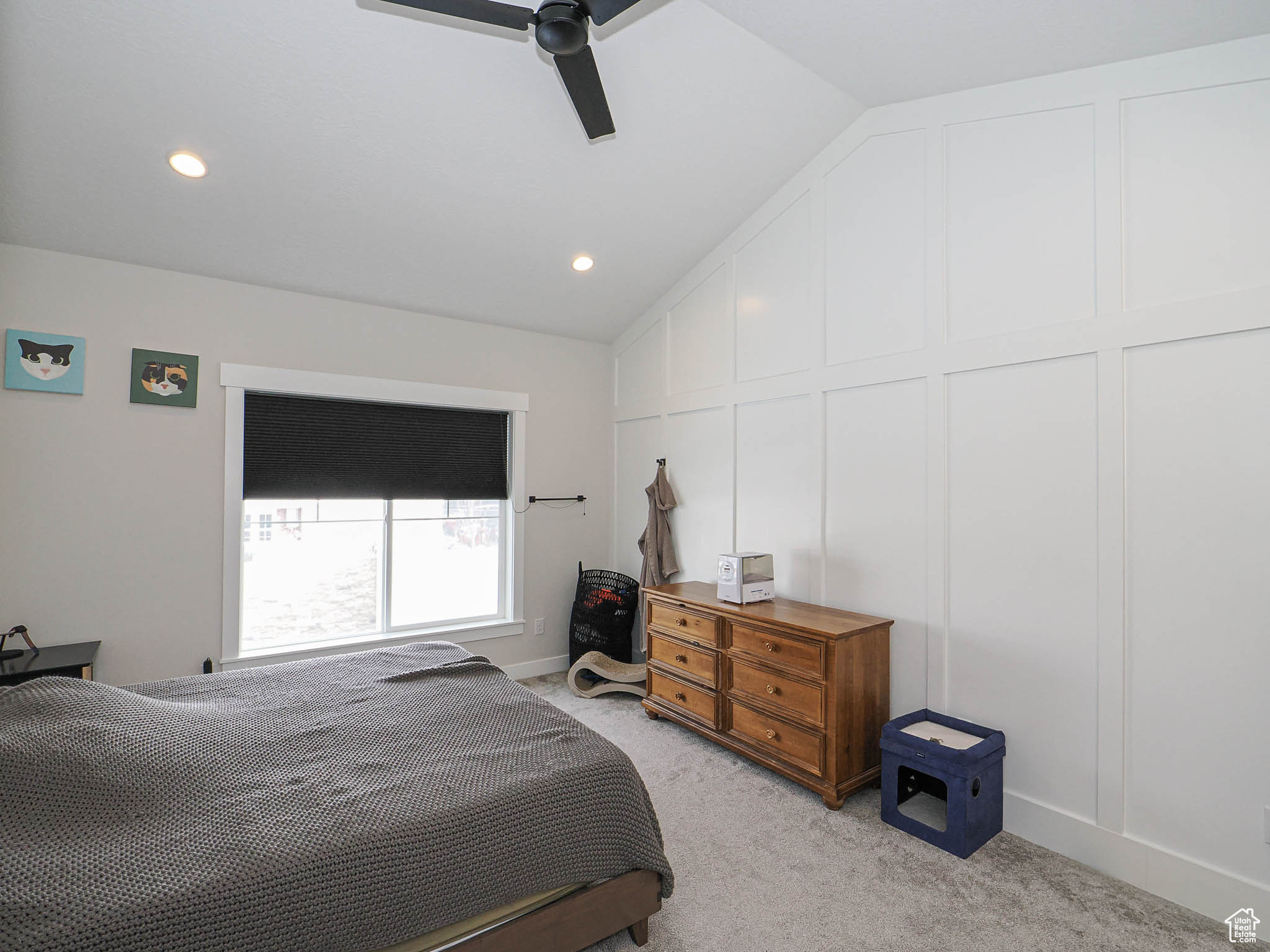 Bedroom with light carpet, vaulted ceiling, a ceiling fan, and a decorative wall