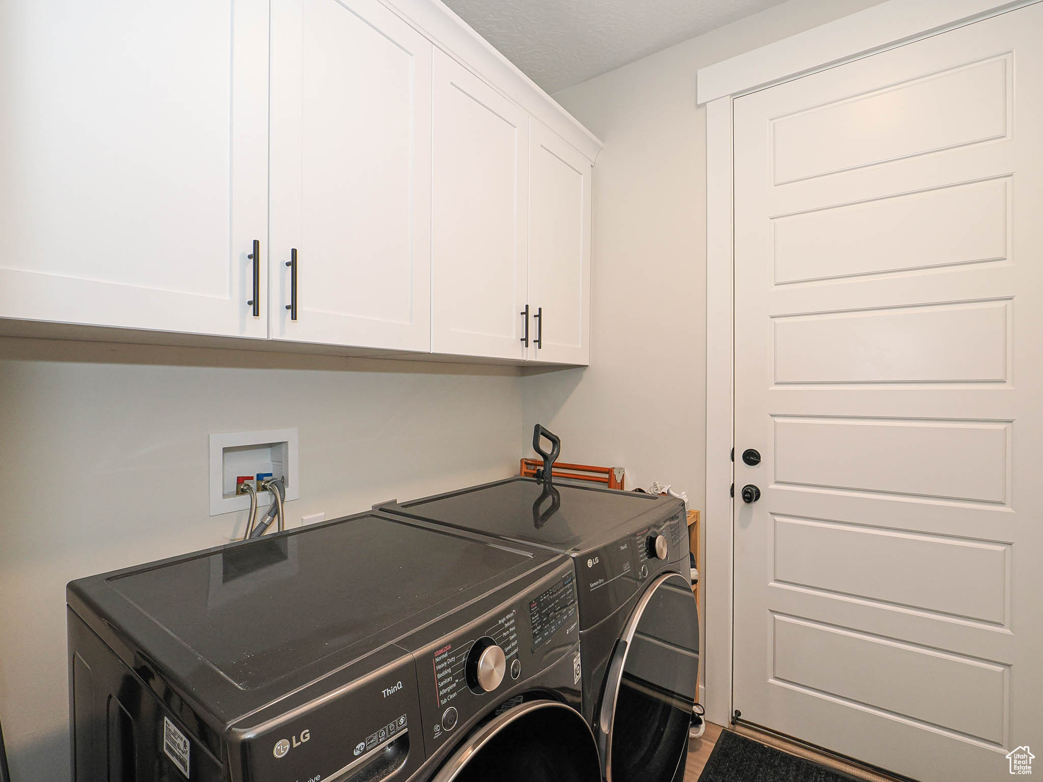 Clothes washing area featuring washer and dryer and cabinet space
