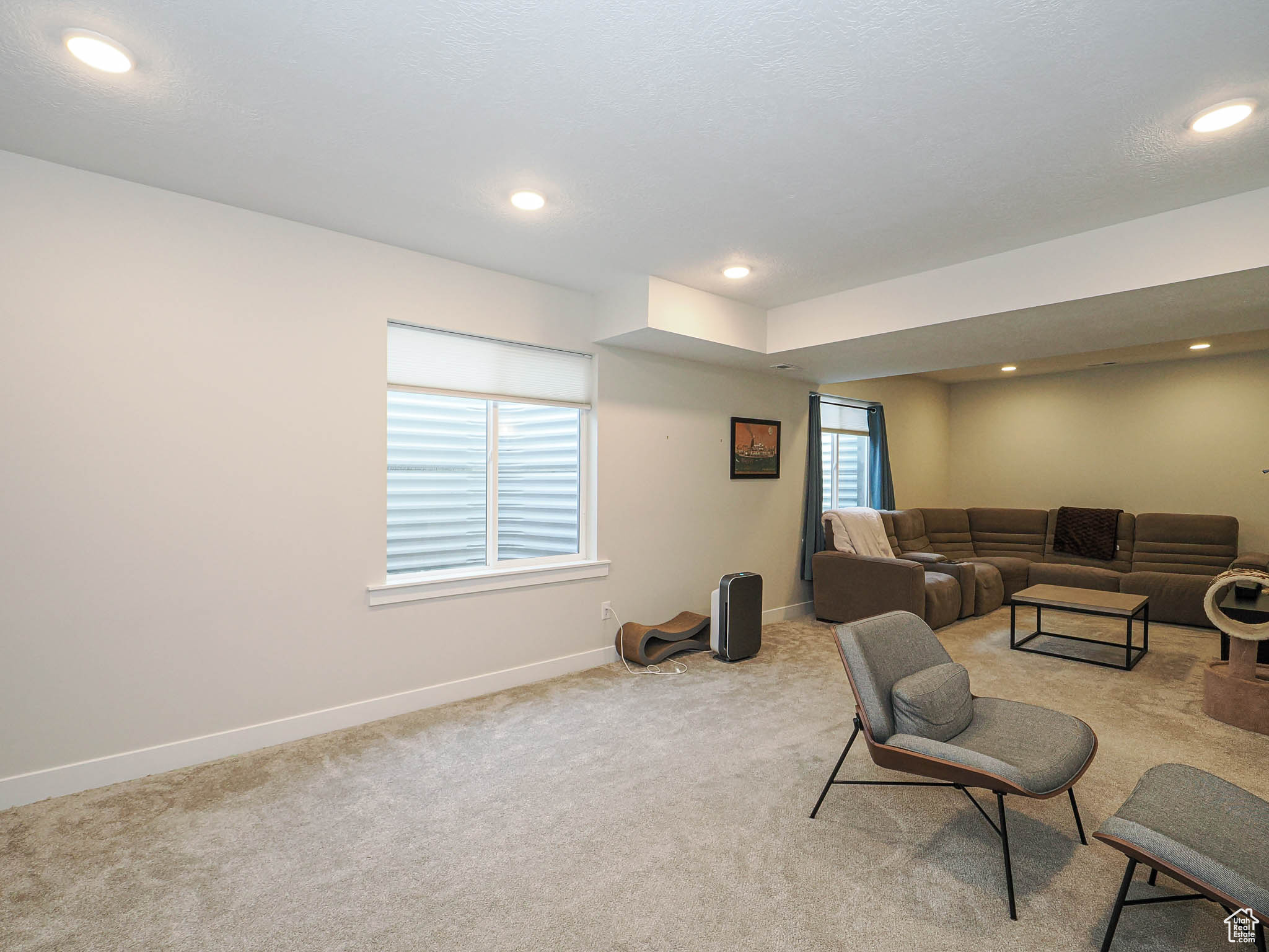 Living room featuring recessed lighting, a healthy amount of sunlight, light colored carpet, and baseboards