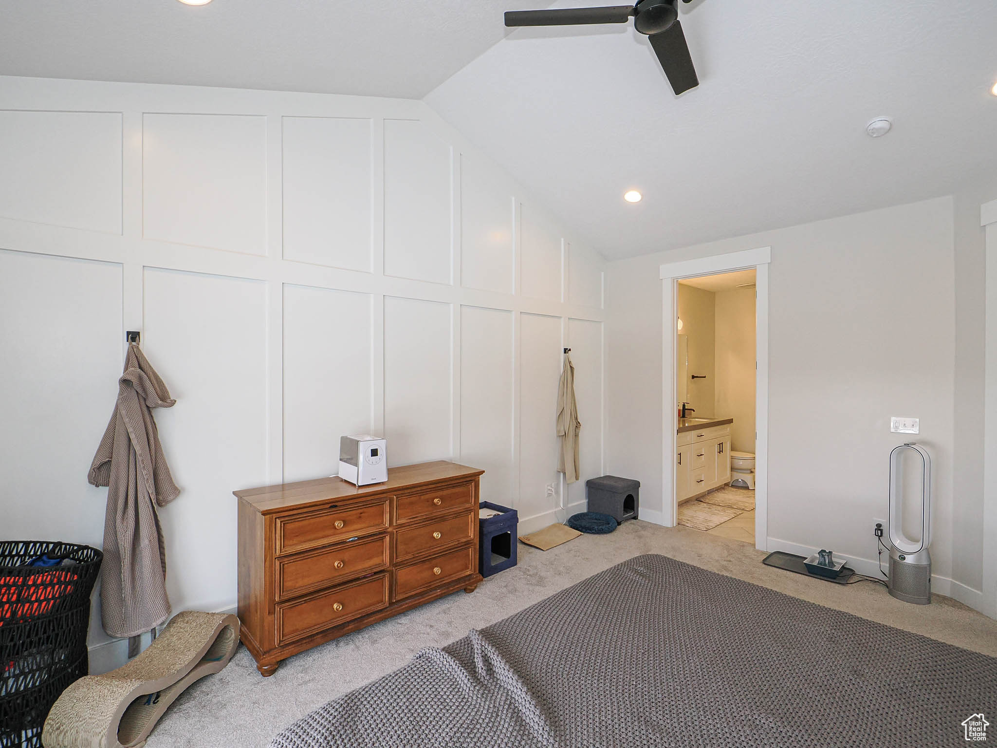 Bedroom featuring connected bathroom, lofted ceiling, light colored carpet, and a decorative wall
