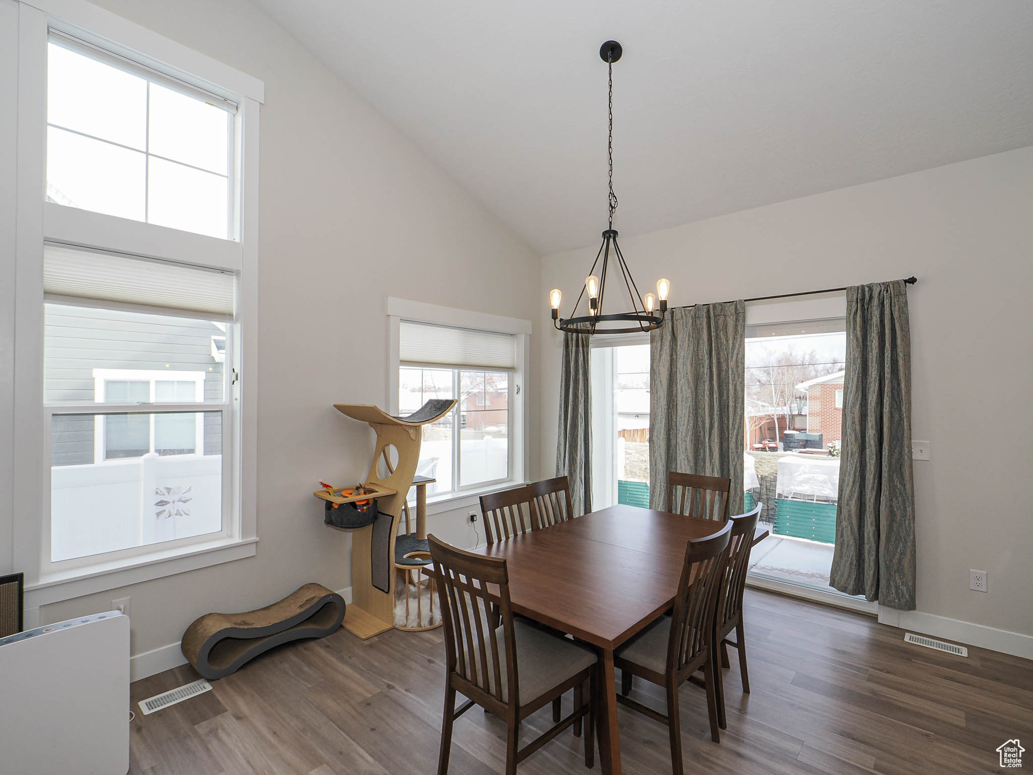 Dining room featuring lofted ceiling, dark wood-style flooring, visible vents, baseboards, and an inviting chandelier