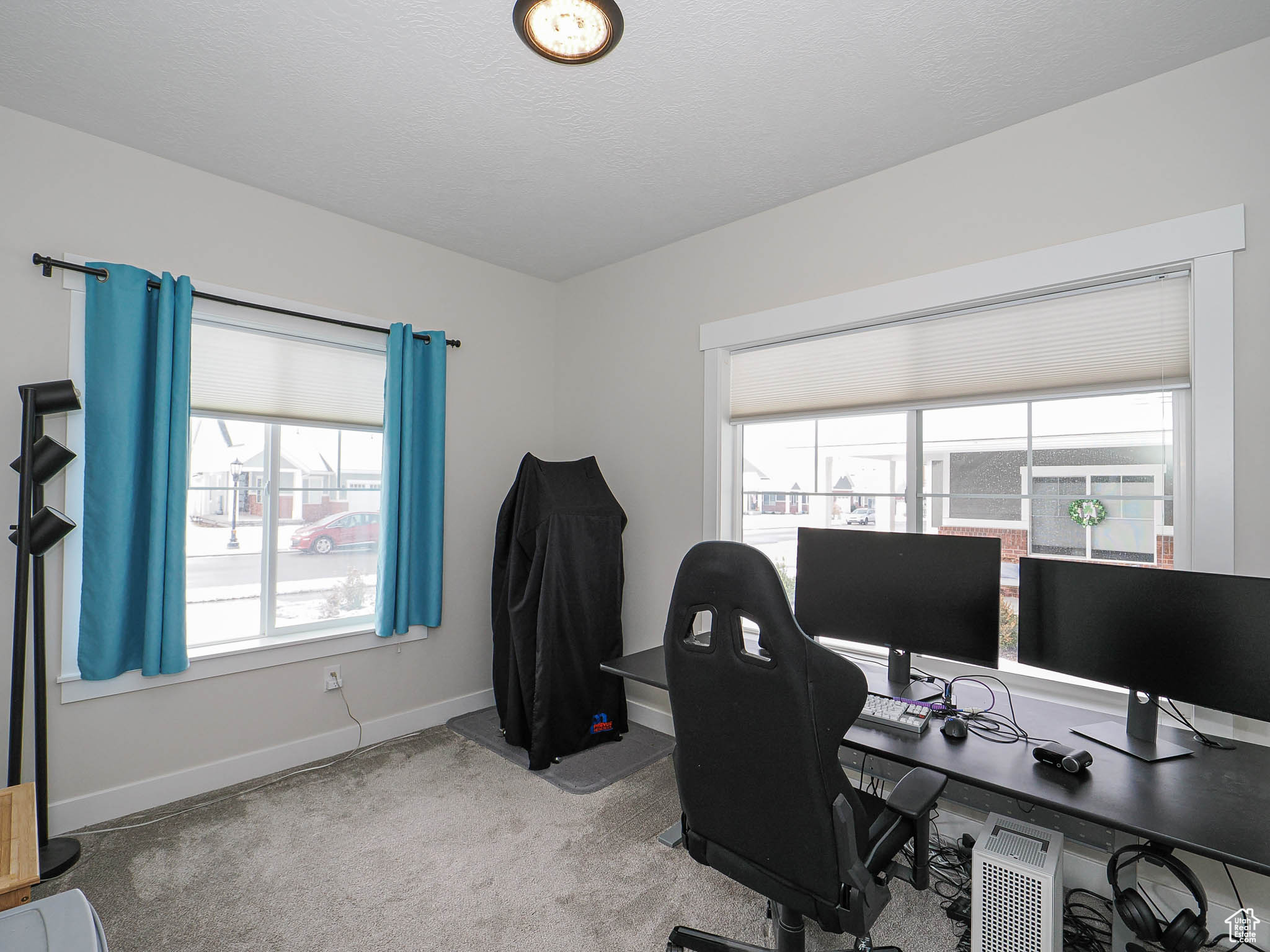 Carpeted office with a textured ceiling and baseboards