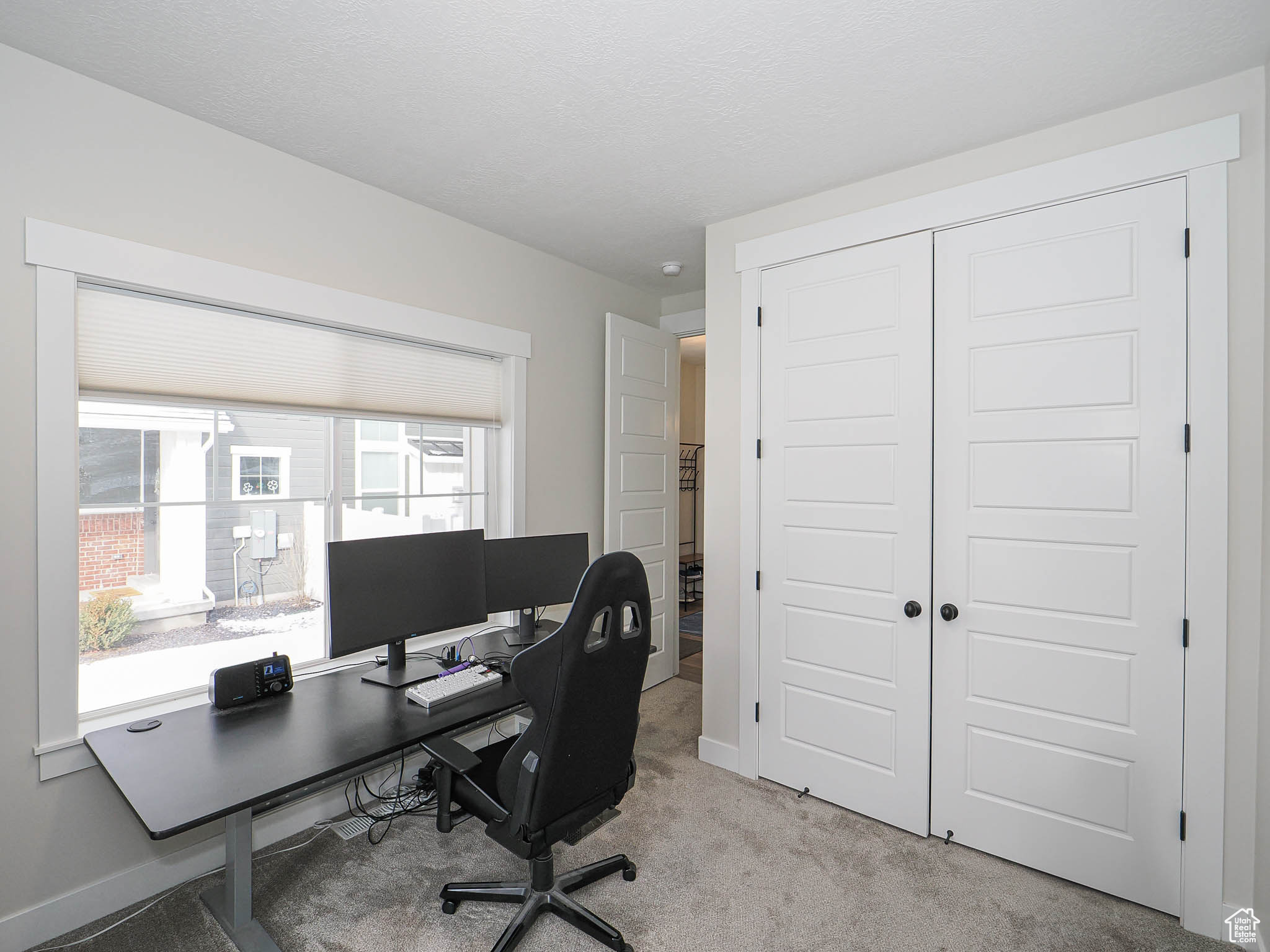 Office space featuring baseboards, a textured ceiling, and light colored carpet
