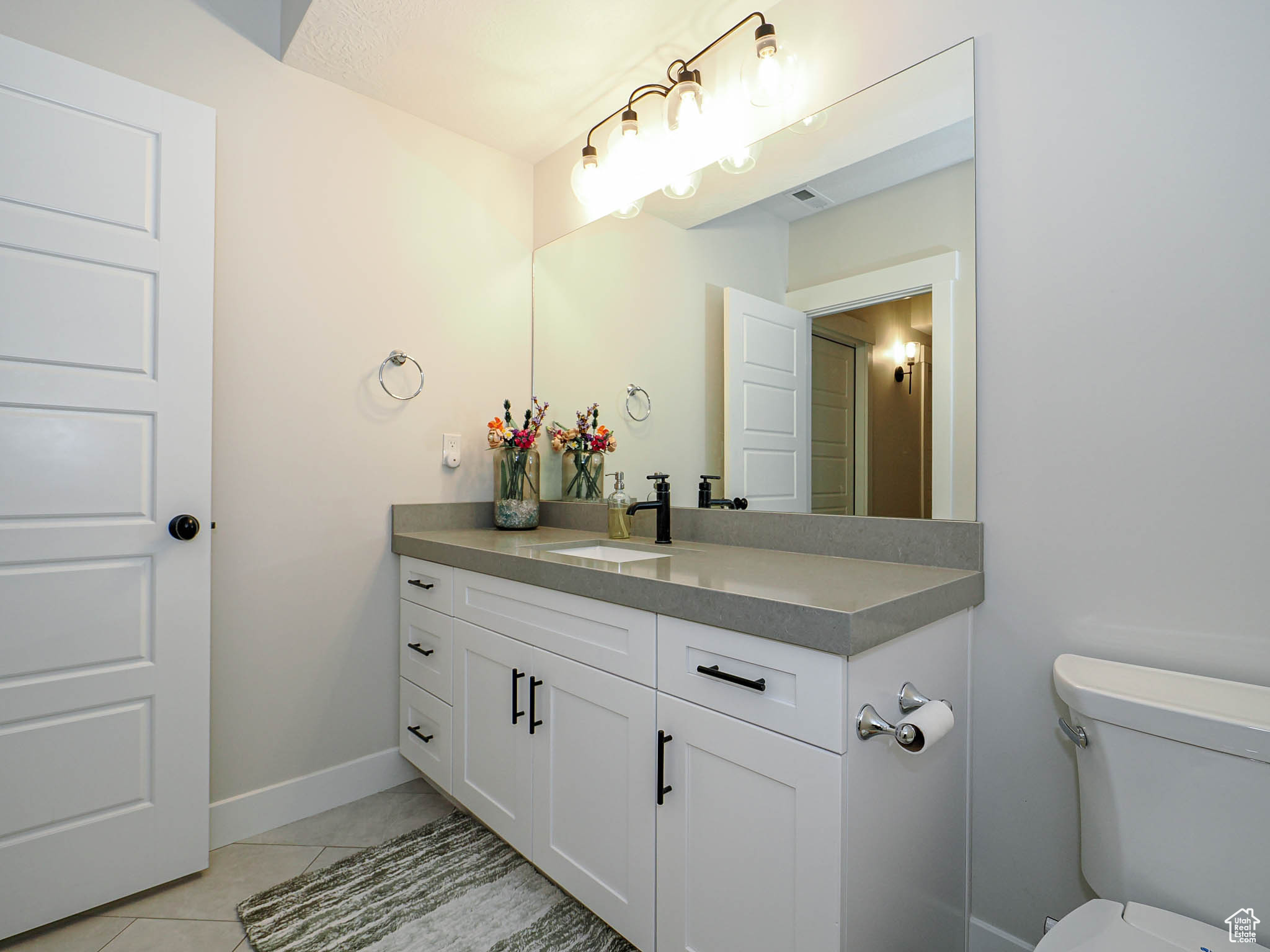 Bathroom featuring toilet, visible vents, baseboards, vanity, and tile patterned floors