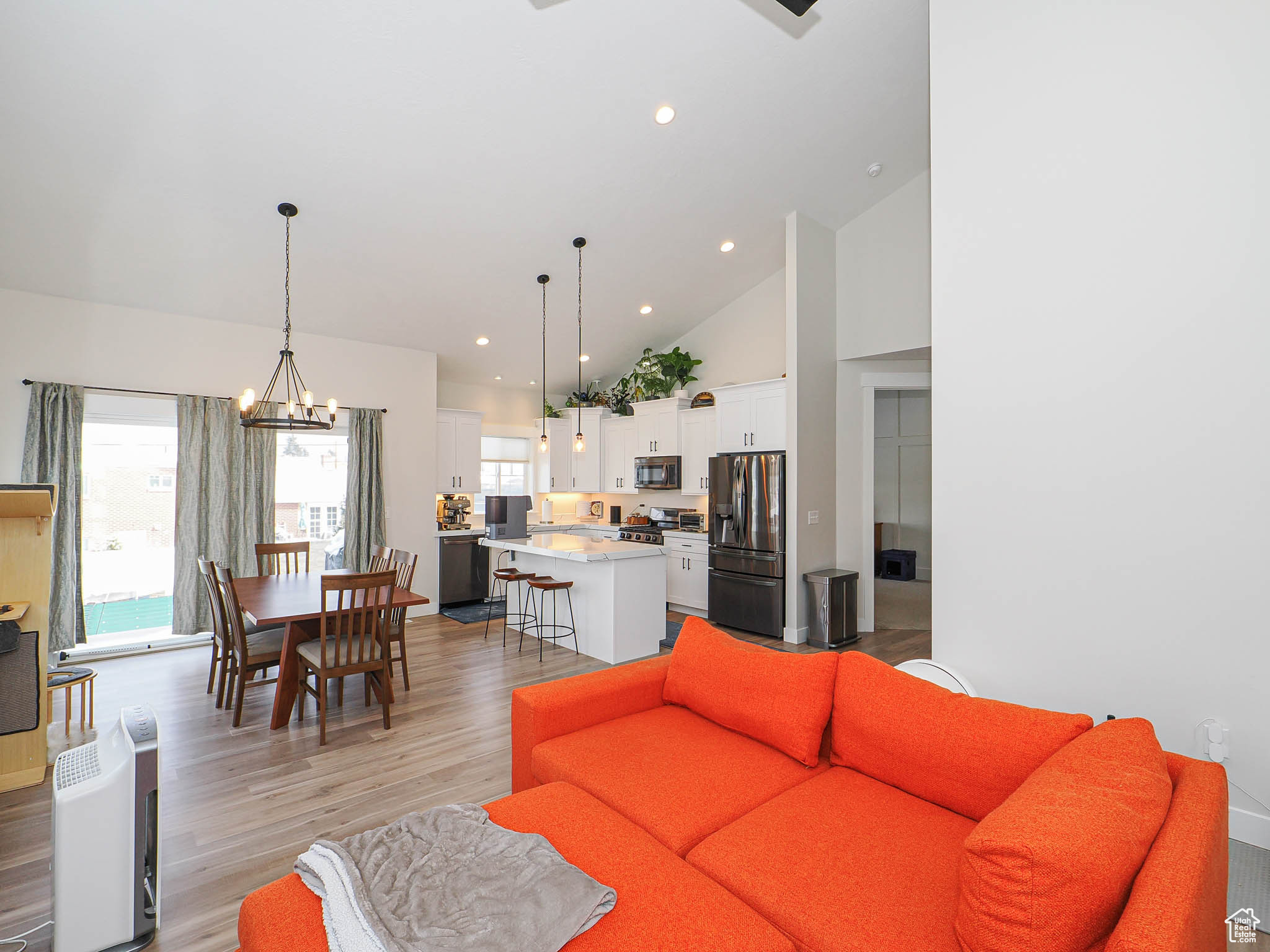 Living room with high vaulted ceiling, recessed lighting, light wood-style flooring, and a notable chandelier