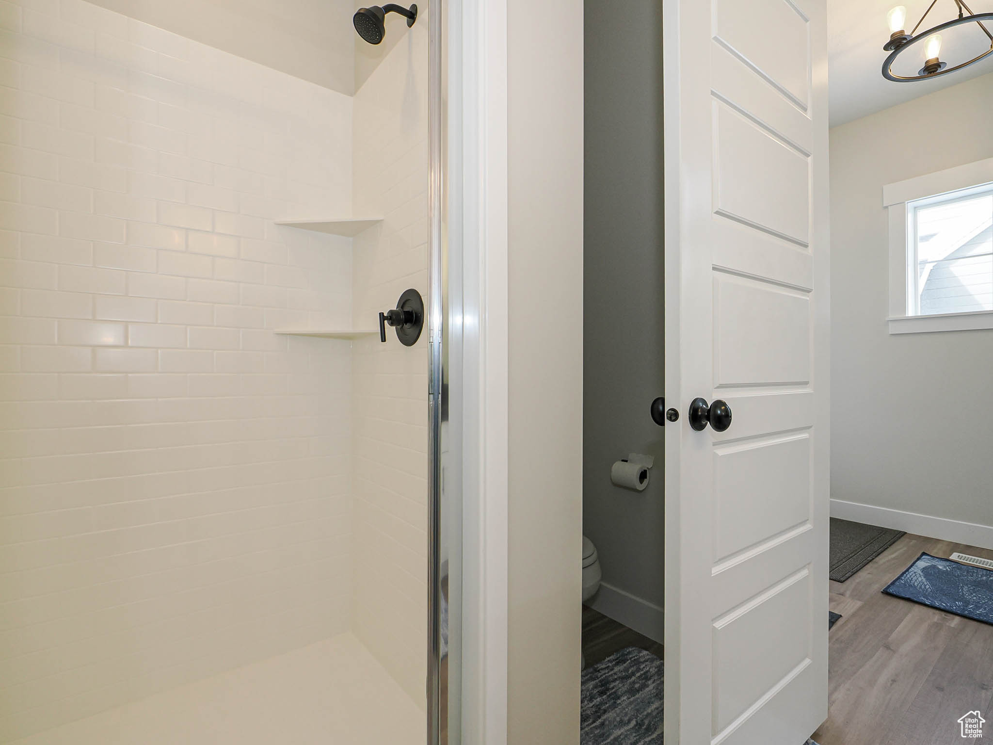 Bathroom with a stall shower, toilet, baseboards, and wood finished floors