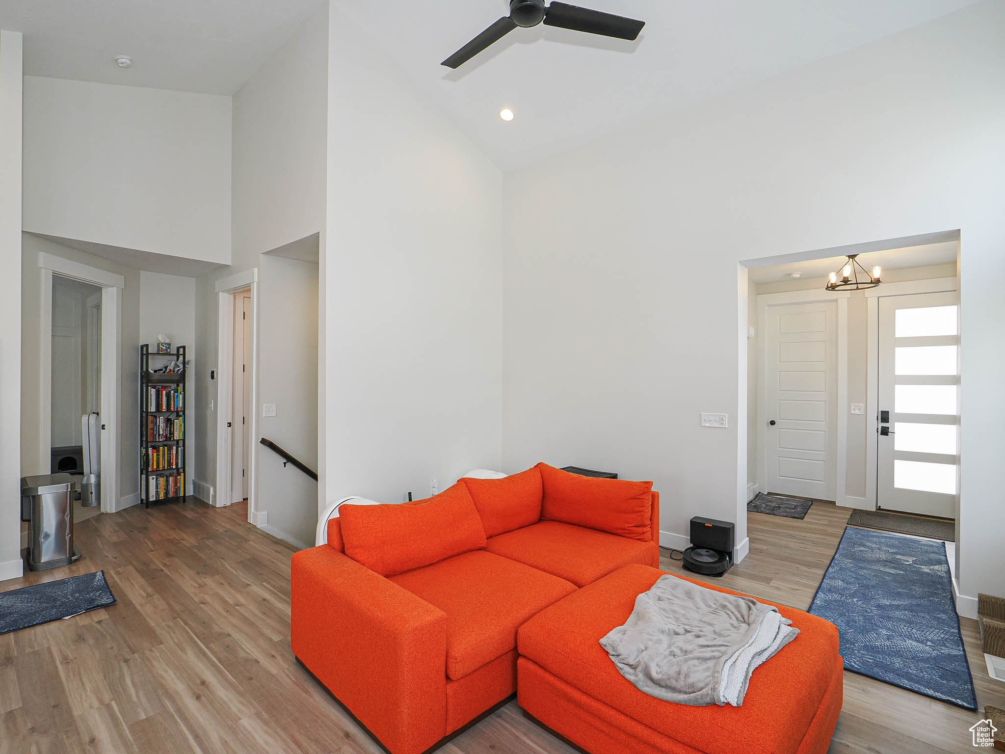 Living room with high vaulted ceiling, recessed lighting, ceiling fan with notable chandelier, wood finished floors, and baseboards