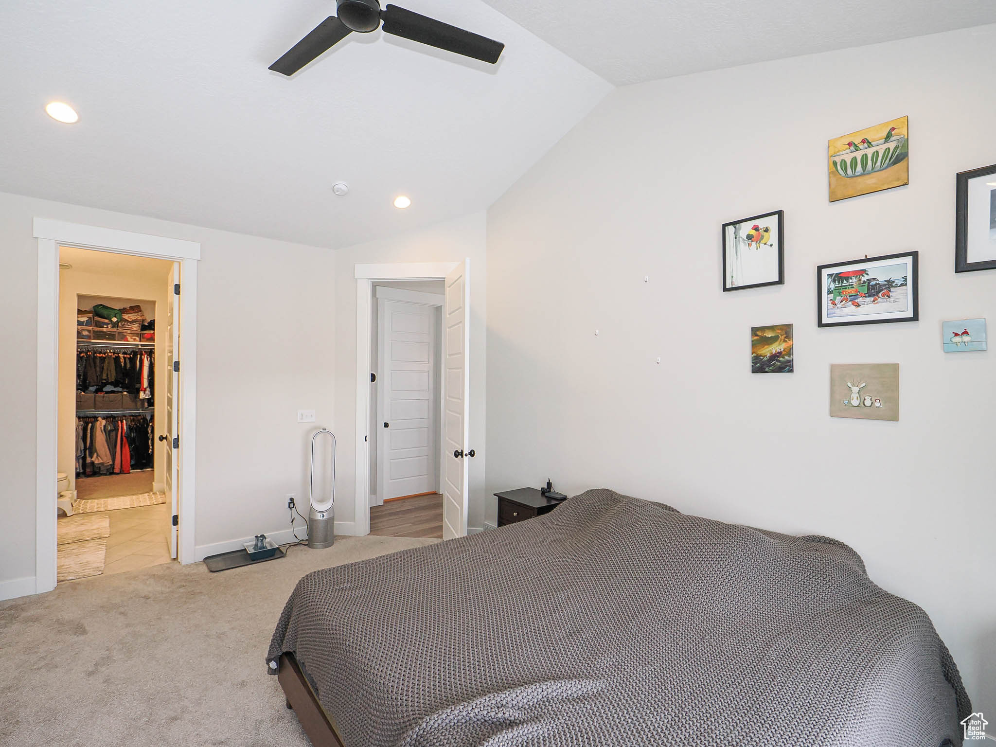 Bedroom with baseboards, light colored carpet, lofted ceiling, a spacious closet, and recessed lighting