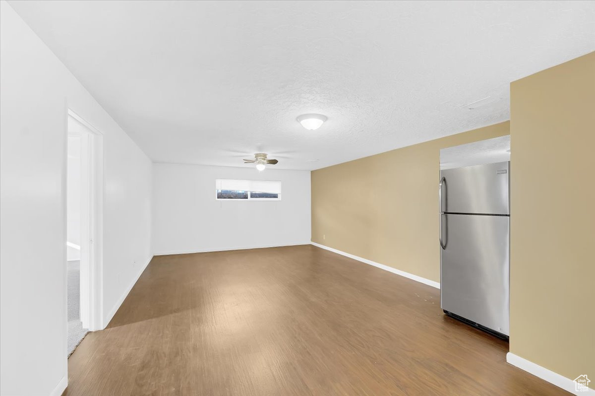 Empty room with baseboards, a textured ceiling, ceiling fan, and wood finished floors