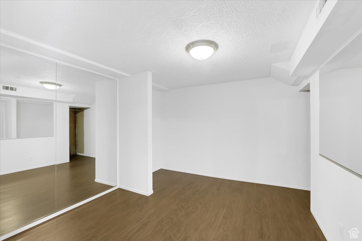 Unfurnished room featuring baseboards, wood finished floors, visible vents, and a textured ceiling