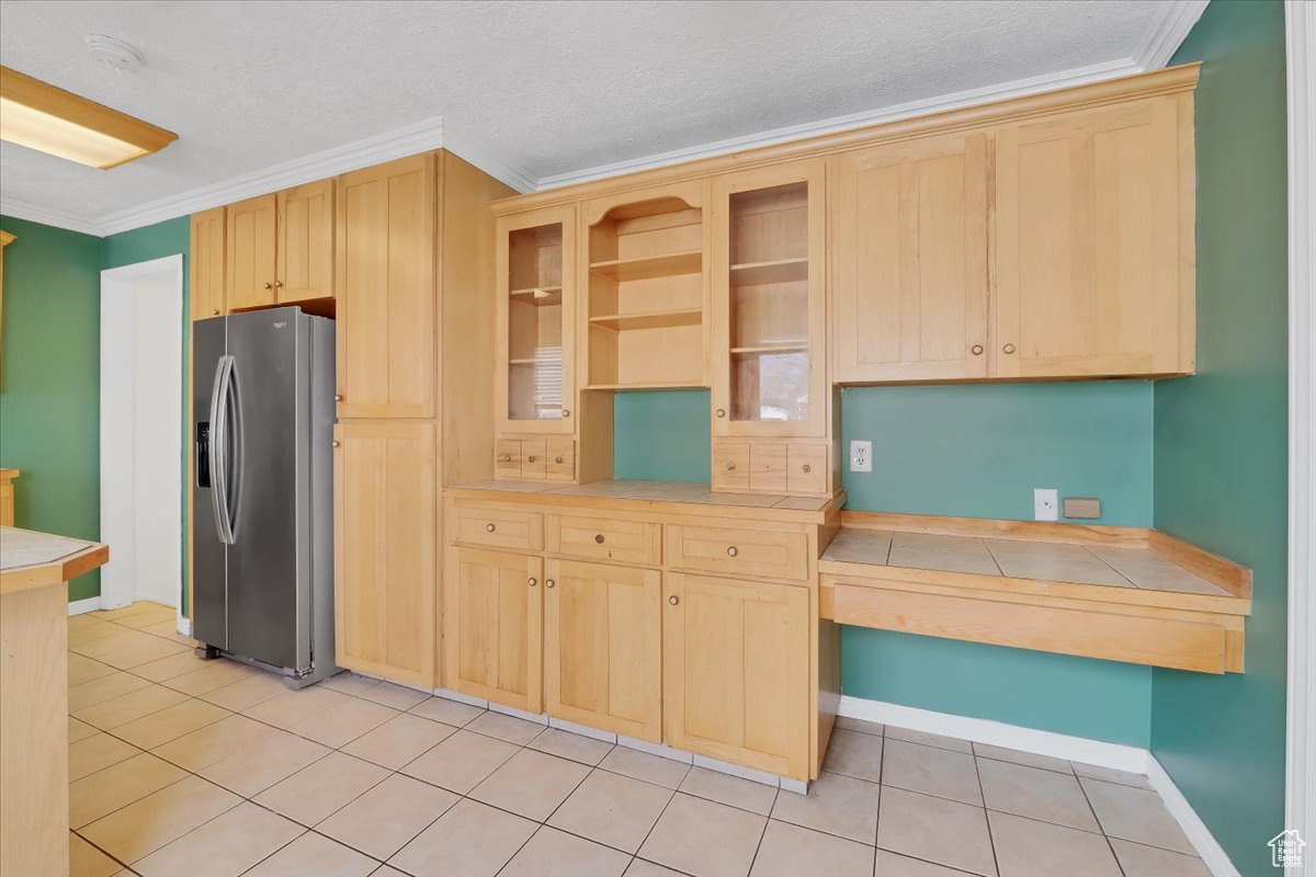 Kitchen featuring stainless steel fridge, light brown cabinets, and crown molding