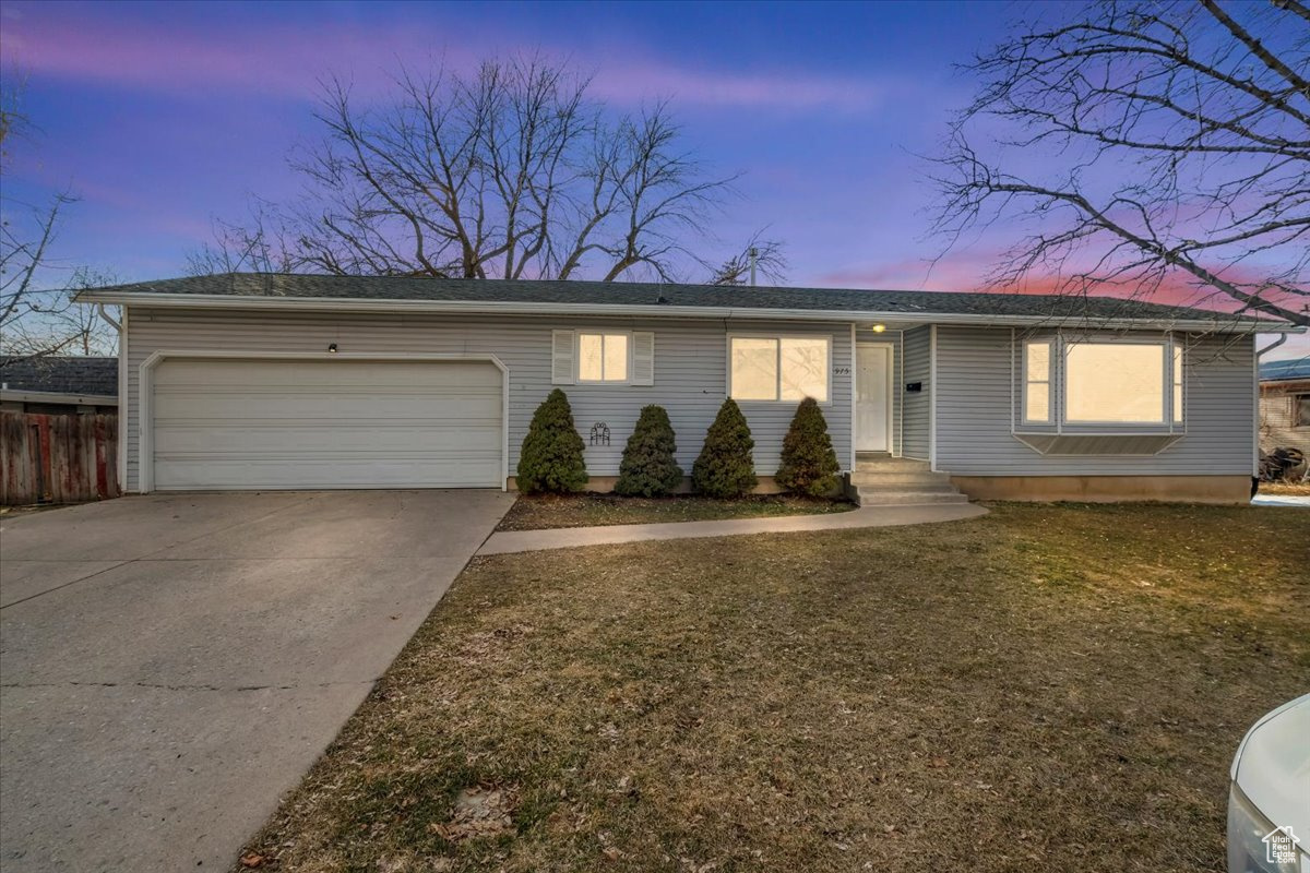 Ranch-style home featuring a garage, concrete driveway, and fence