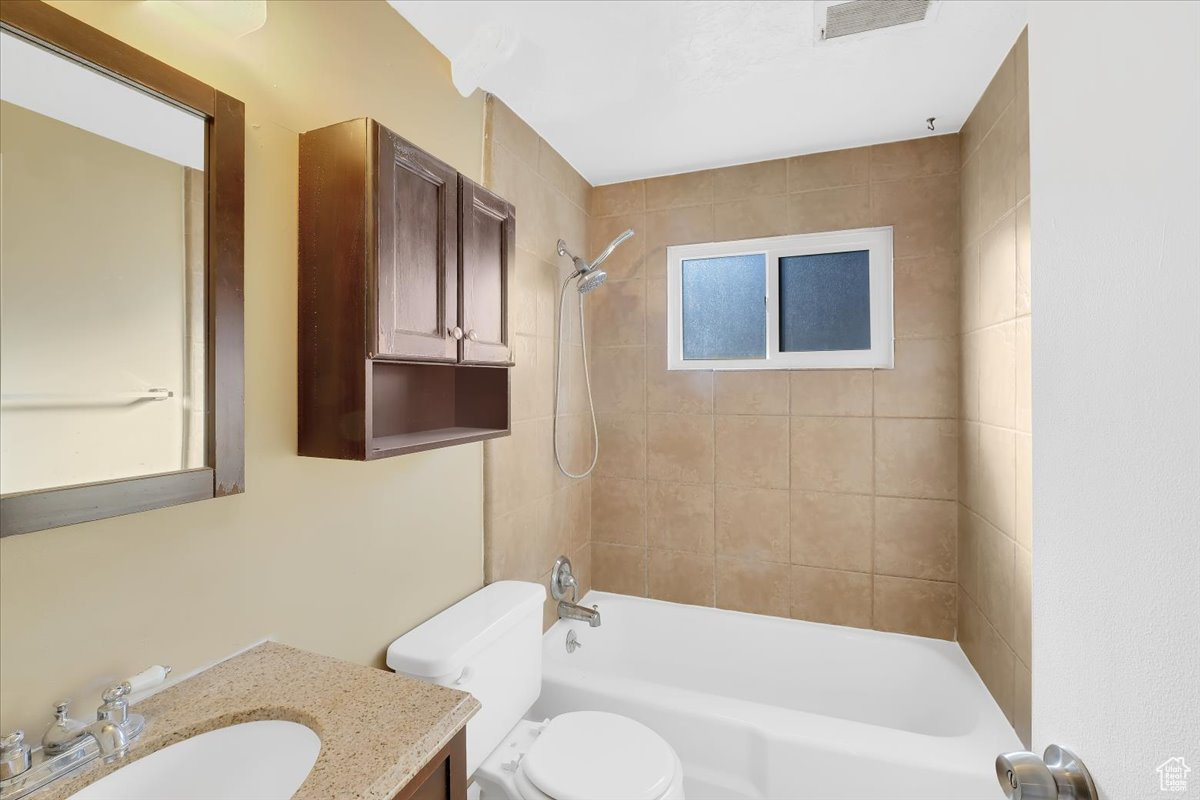 Bathroom featuring vanity, toilet, visible vents, and shower / washtub combination