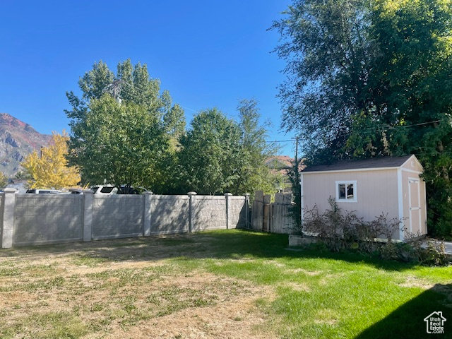 View of yard with an outbuilding, a storage unit, and fence