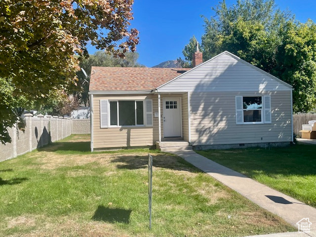 View of front of house featuring a chimney, a front lawn, and fence