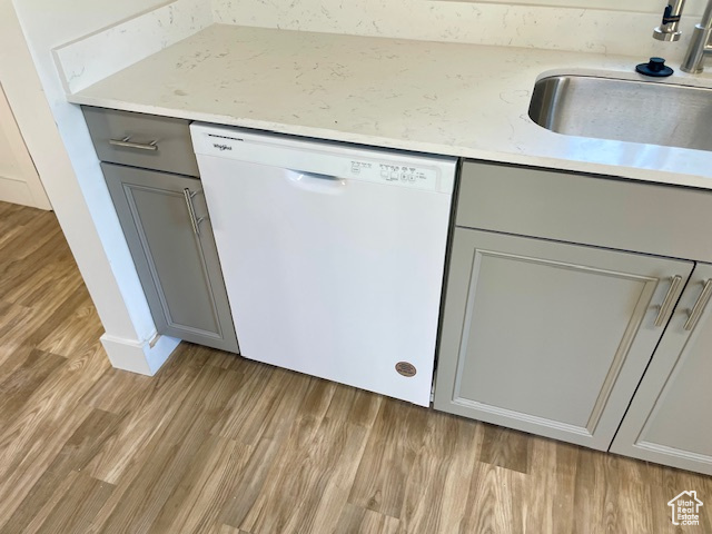 Interior details featuring light wood-type flooring, gray cabinets, white dishwasher, and a sink