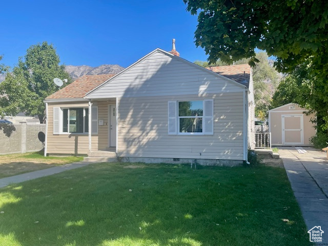 View of front of house featuring a front yard, an outdoor structure, fence, and a shed