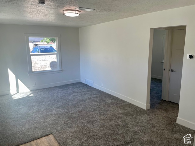 Empty room featuring visible vents, carpet floors, a textured ceiling, and baseboards