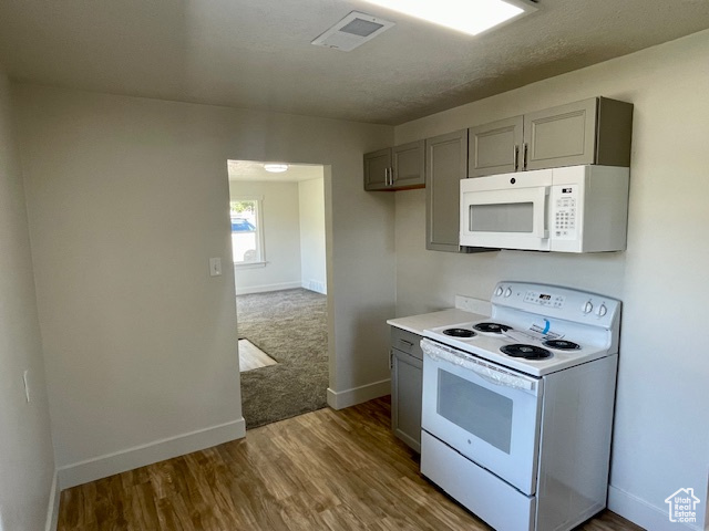 Kitchen with visible vents, dark wood finished floors, light countertops, gray cabinets, and white appliances