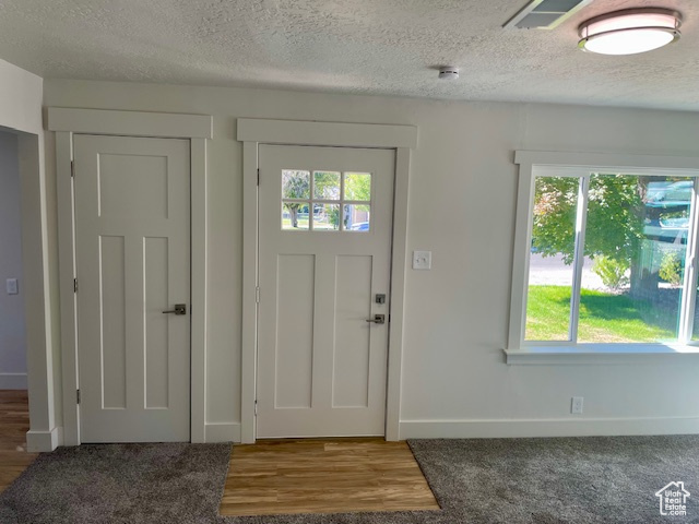 Entrance foyer featuring a textured ceiling, baseboards, and wood finished floors