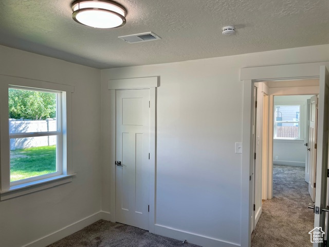 Unfurnished bedroom featuring visible vents, multiple windows, baseboards, and carpet