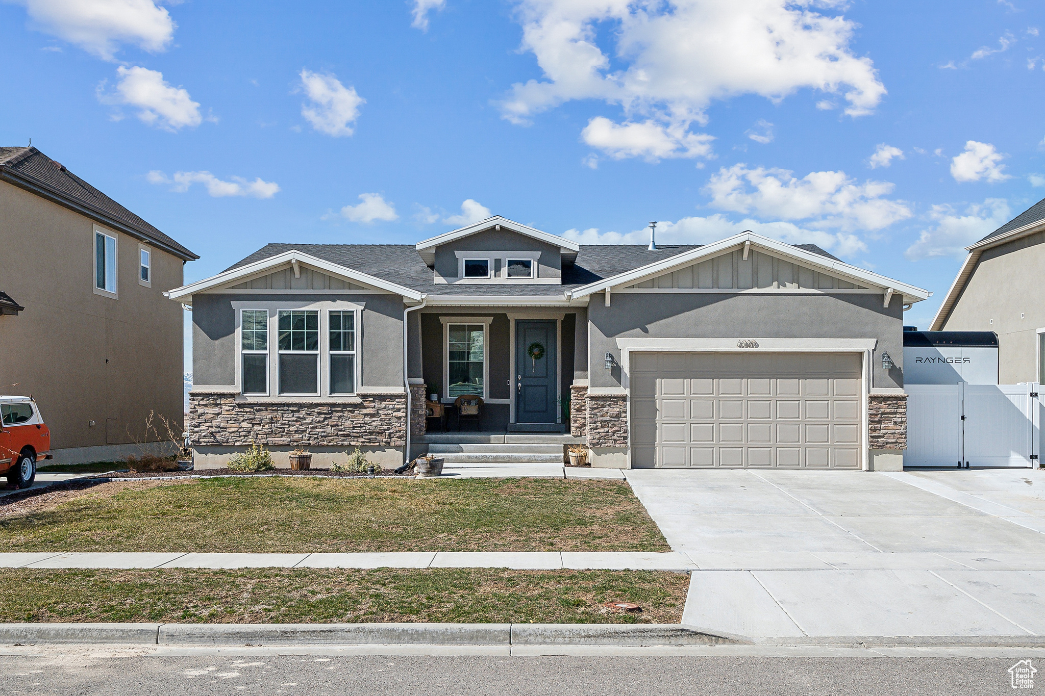 Craftsman house featuring a front yard, a gate, driveway, an attached garage, and stone siding