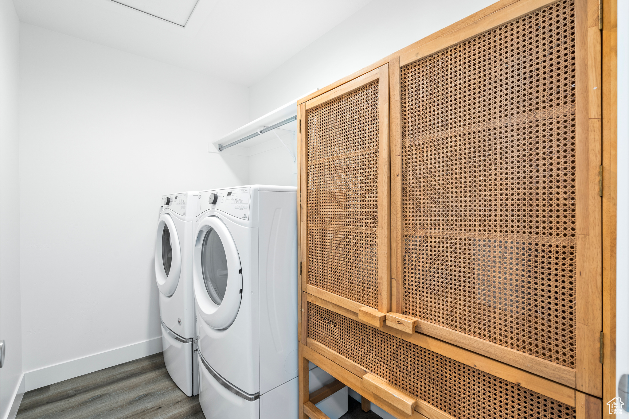 Laundry room with dark wood finished floors, laundry area, washer and dryer, and baseboards