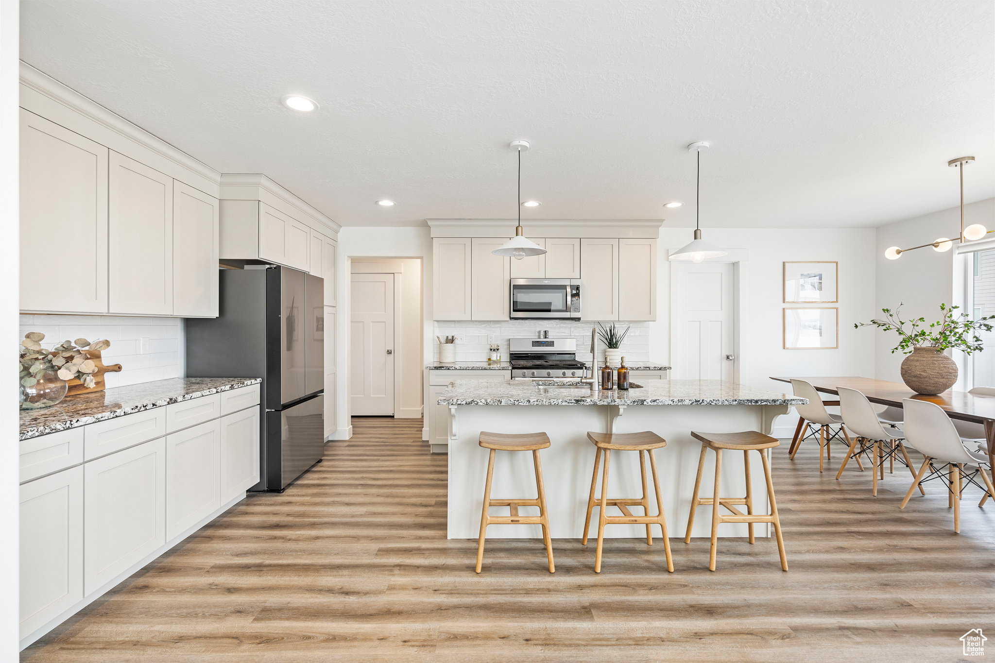 Kitchen with light wood-style flooring, an island with sink, a breakfast bar area, and stainless steel appliances
