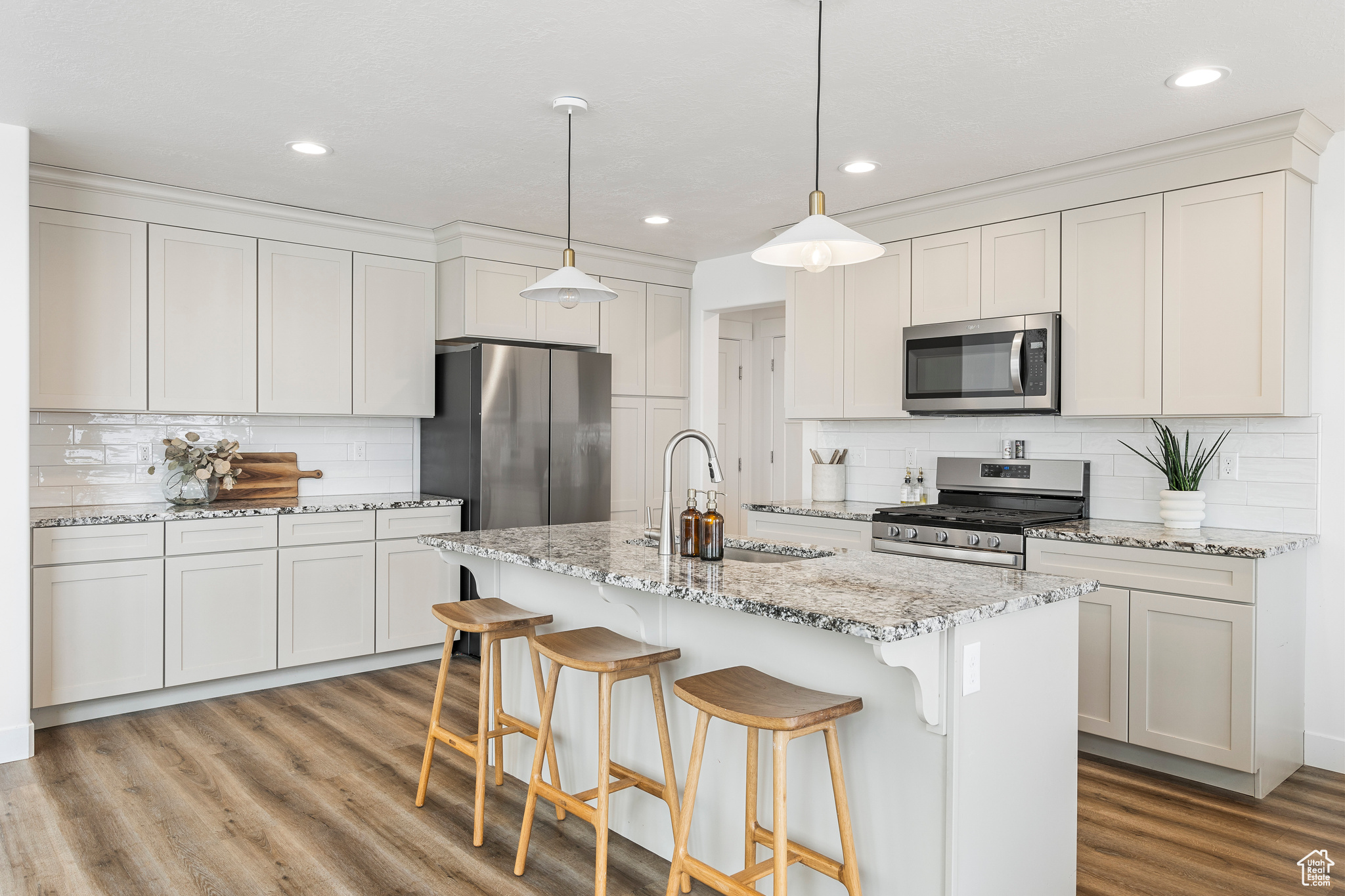 Kitchen with light wood-style flooring, appliances with stainless steel finishes, a kitchen bar, and a sink