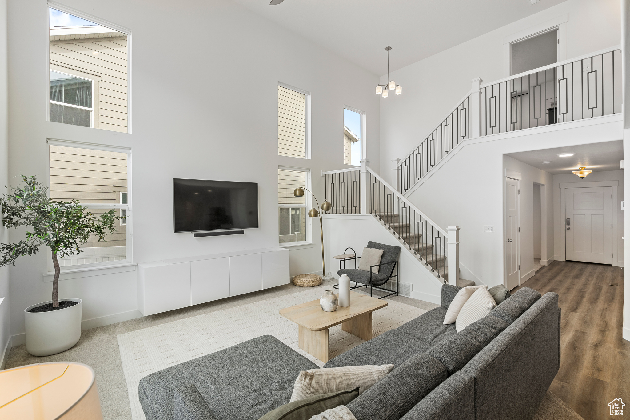 Living area with stairway, baseboards, a notable chandelier, and a towering ceiling