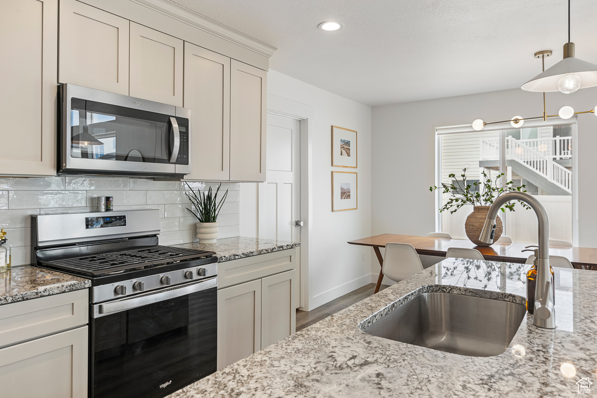 Kitchen featuring tasteful backsplash, appliances with stainless steel finishes, pendant lighting, and a sink