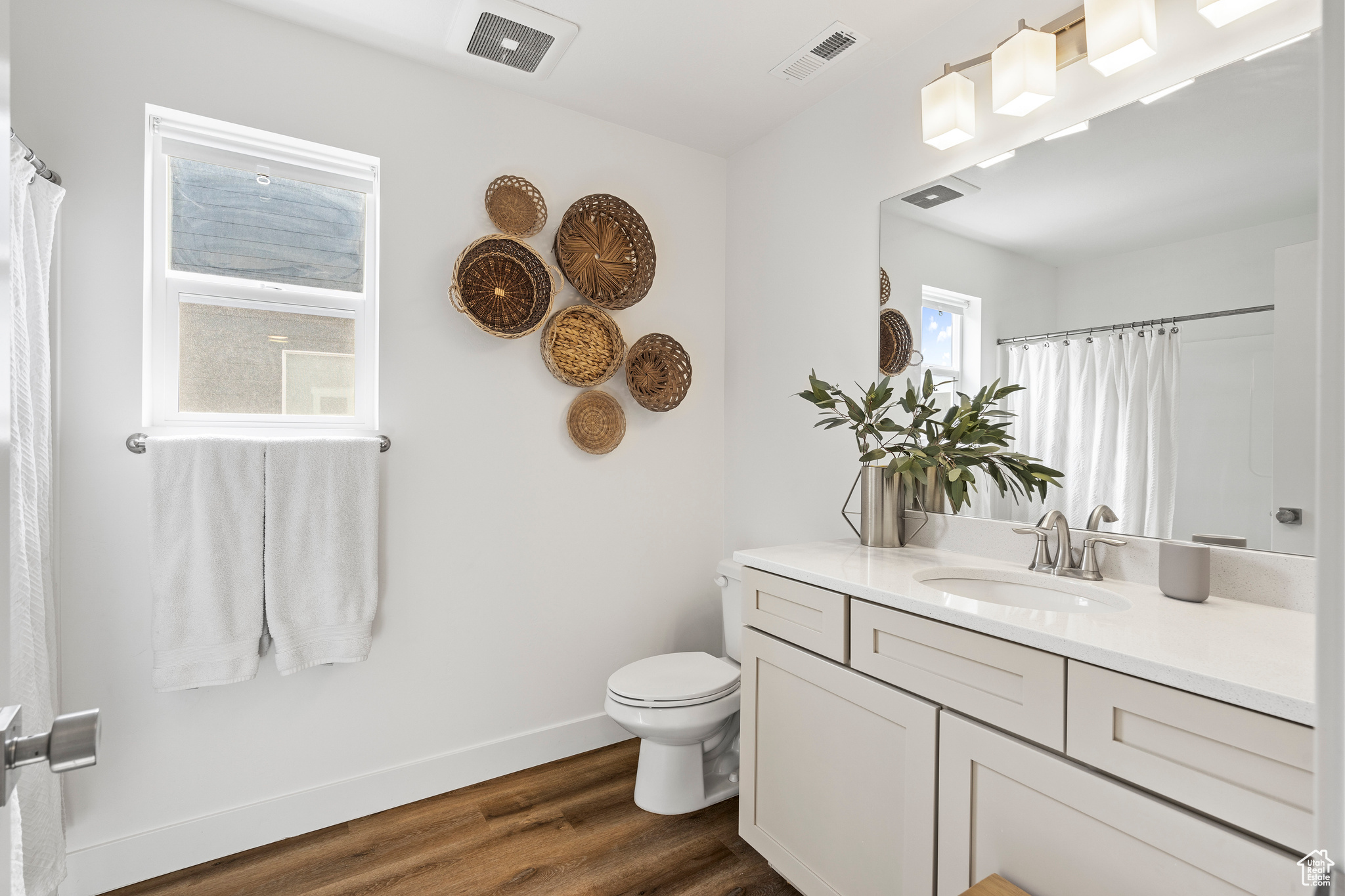 Full bathroom featuring visible vents, toilet, wood finished floors, baseboards, and vanity