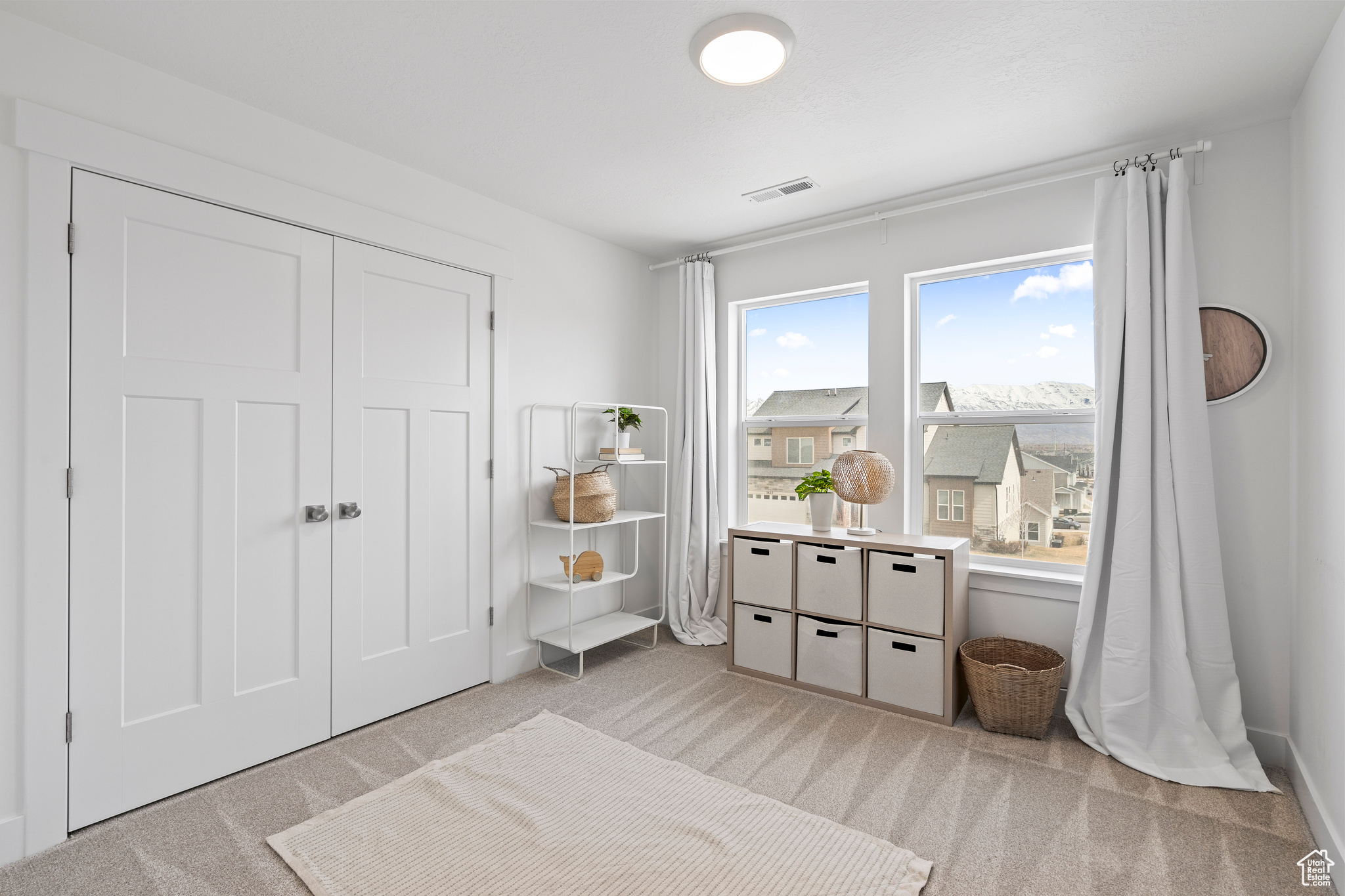 Bedroom with a closet, light colored carpet, and visible vents